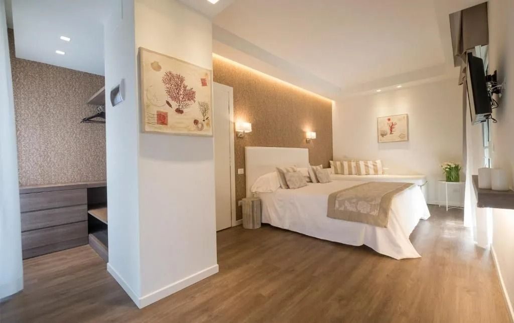 Camera da letto con pavimenti in legno, letto king-size e armadio a muro. Colori neutri e design moderno.