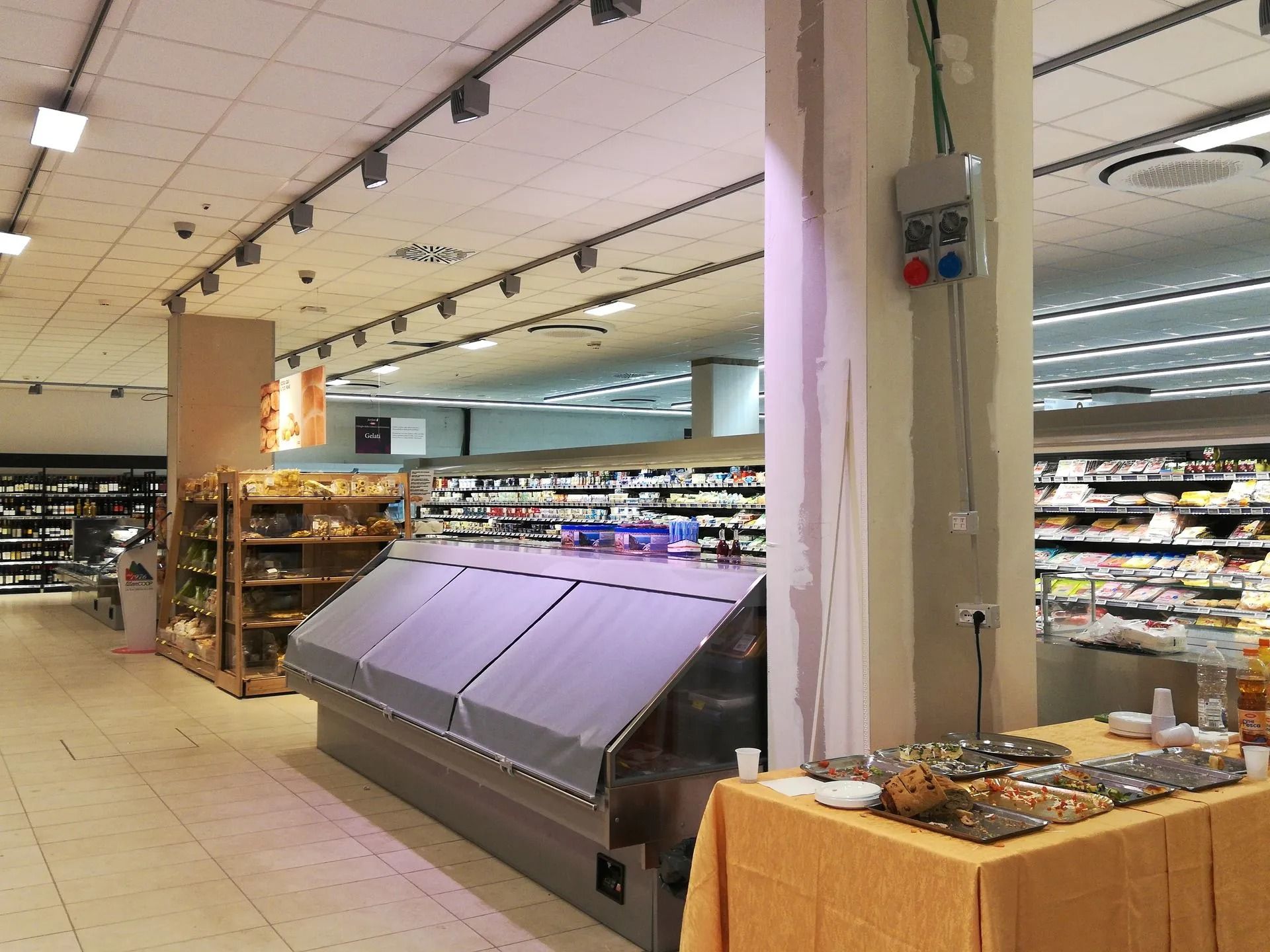 Corsia del supermercato con vetrina refrigerata, scaffali e illuminazione dall'alto.