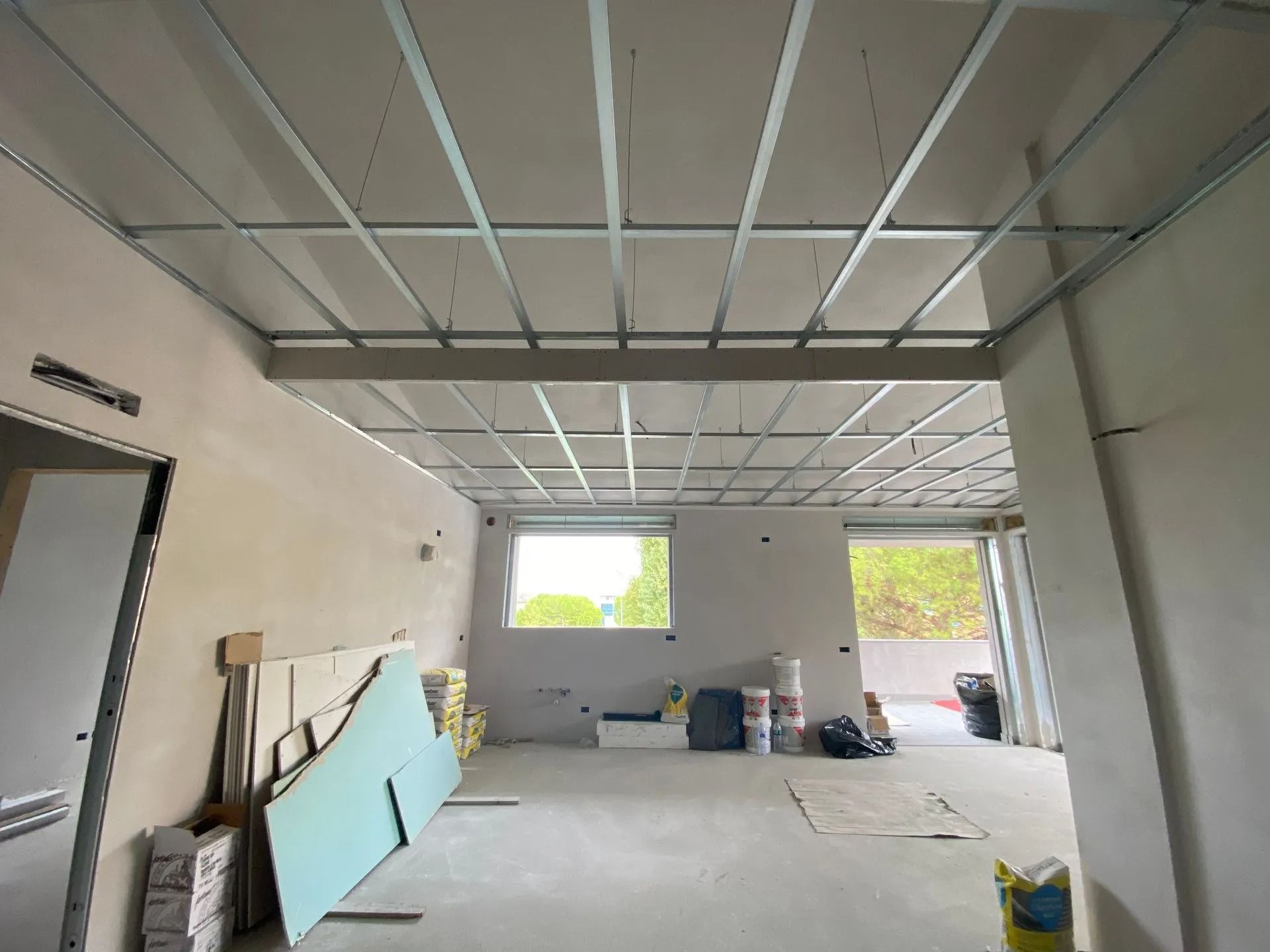 Interno di una stanza in costruzione con installata una struttura del controsoffitto in griglia metallica.
