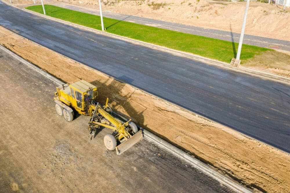 A man wearing gloves is driving a bulldozer on a construction site.
