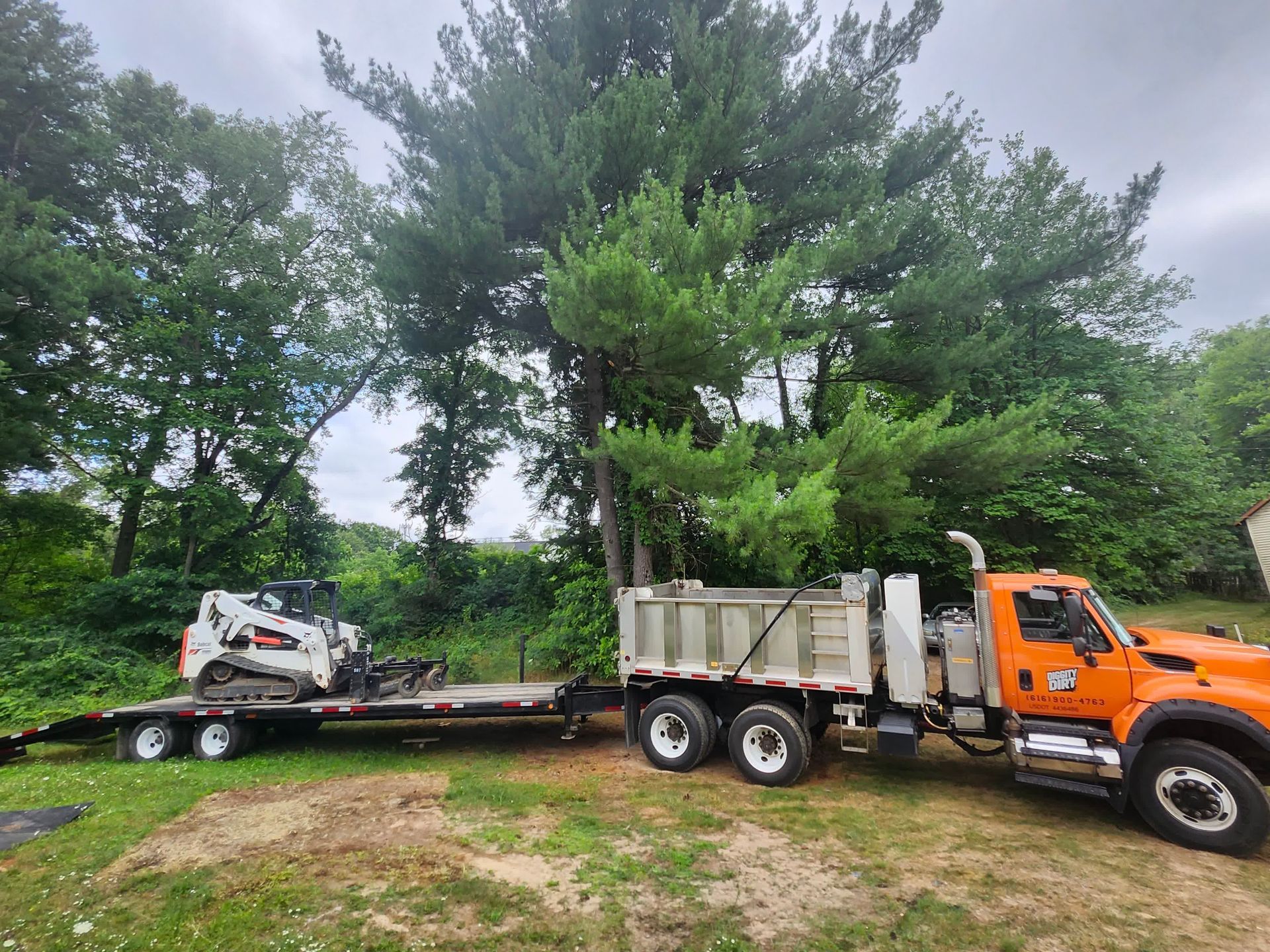 Yellow excavator on a dirt surface with trees in the background.