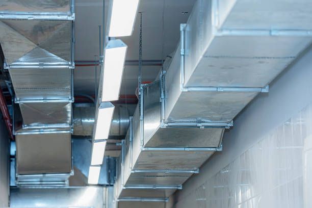 HVAC ductwork, silver rectangular metal, along a white ceiling, with recessed lighting.