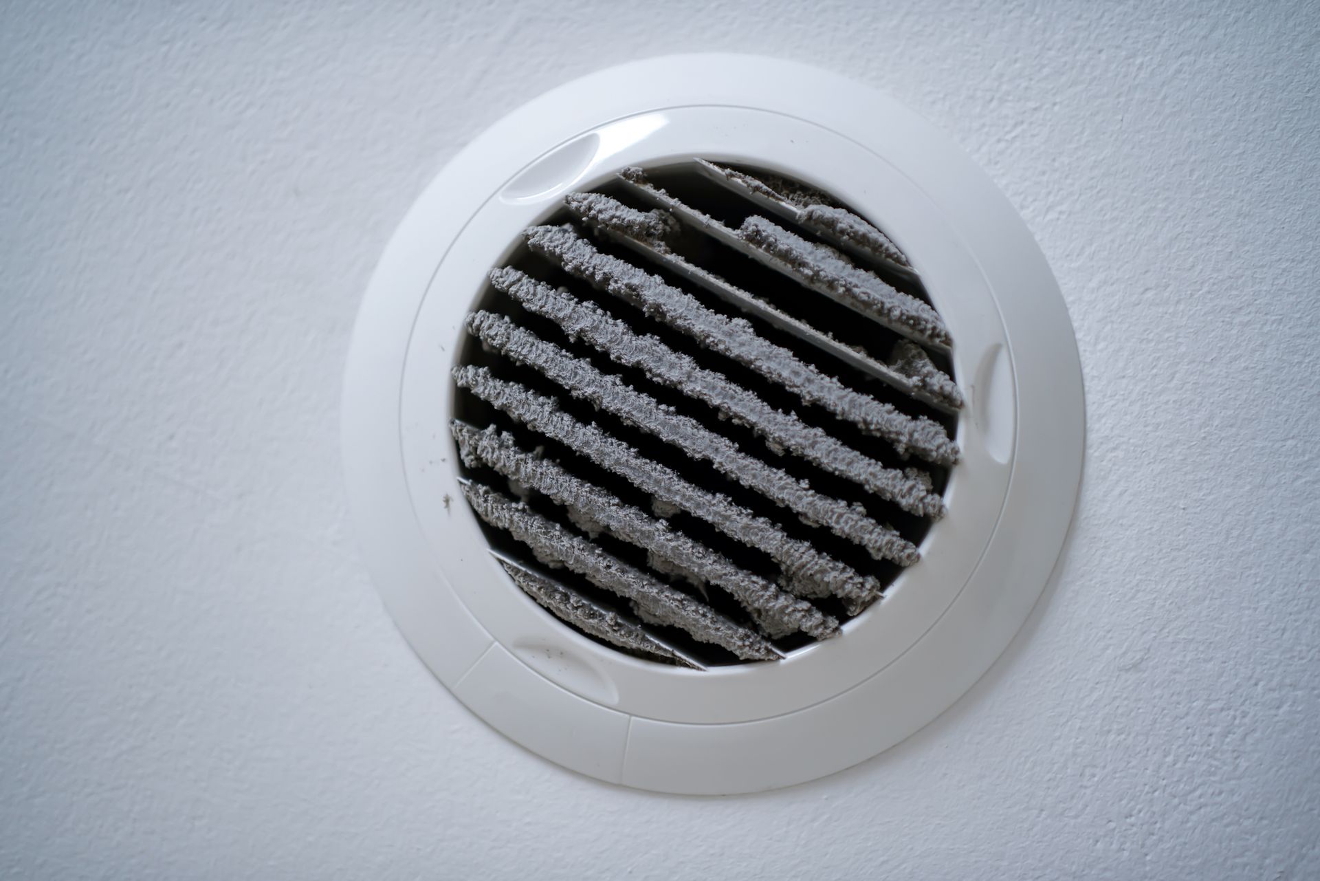 Dirty air vent in a white ceiling. The vent cover is caked in gray dust. Dirty air vent in a white ceiling. The vent cover is caked in gray dust.