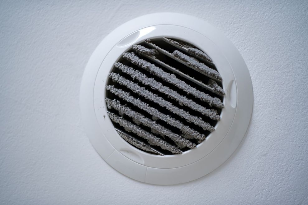 Dirty air vent in a white ceiling. The vent cover is caked in gray dust. Dirty air vent in a white ceiling. The vent cover is caked in gray dust.