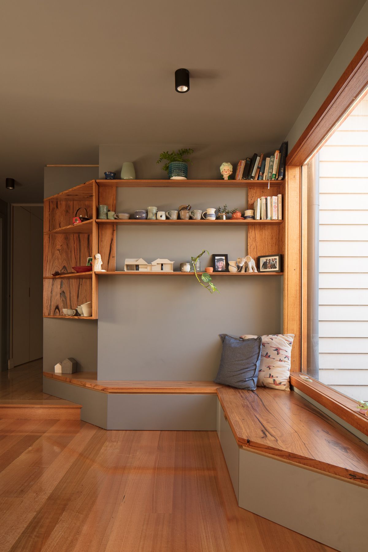 A living room with a window seat and shelves.