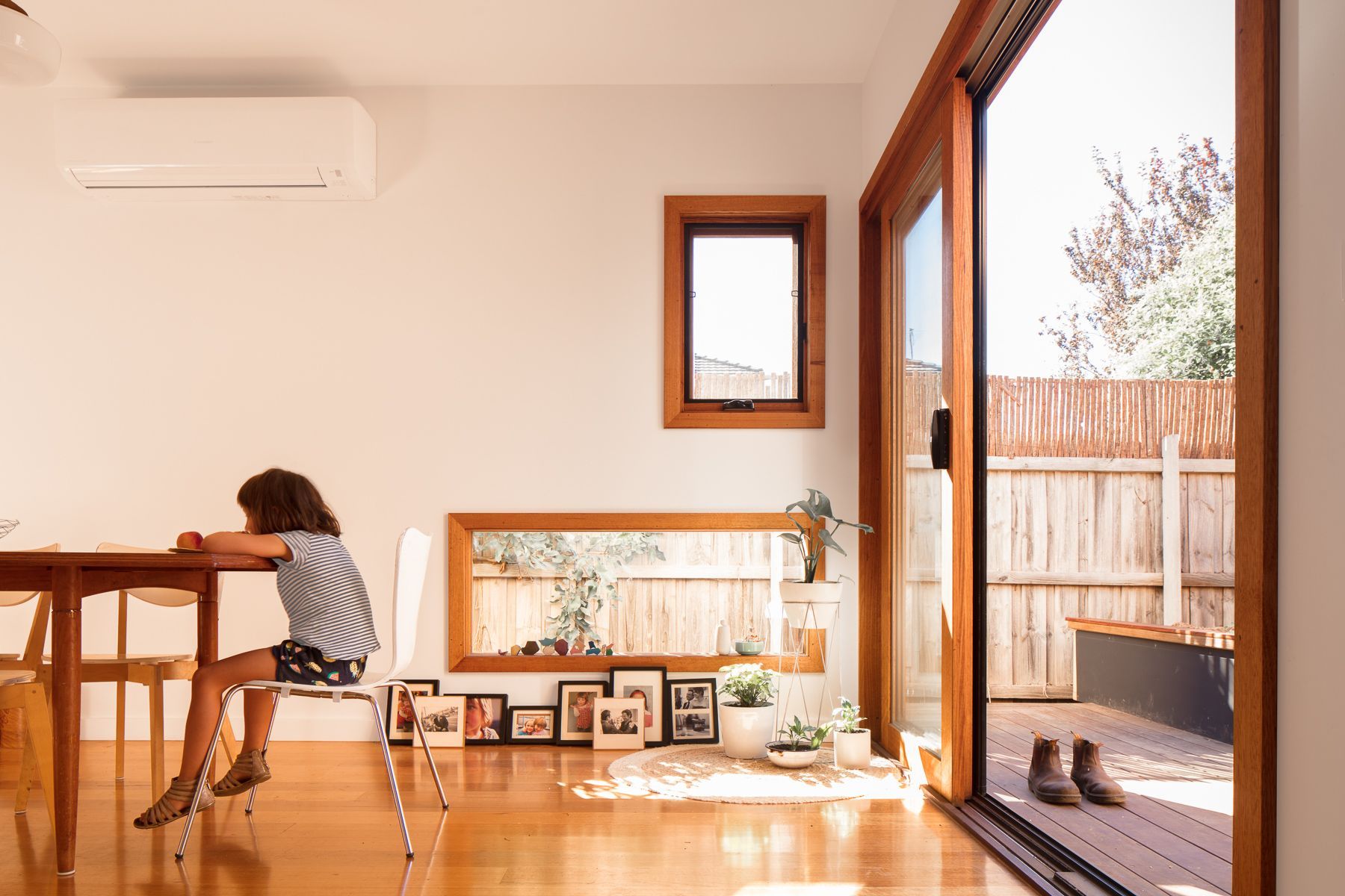A woman is sitting at a table in a living room with a sliding glass door.