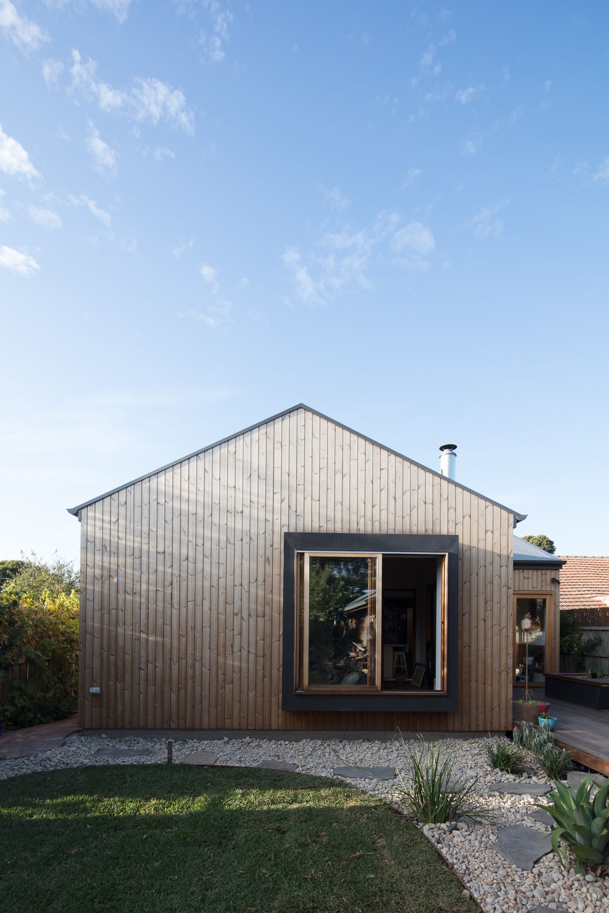 A small wooden house with a large window in the backyard.