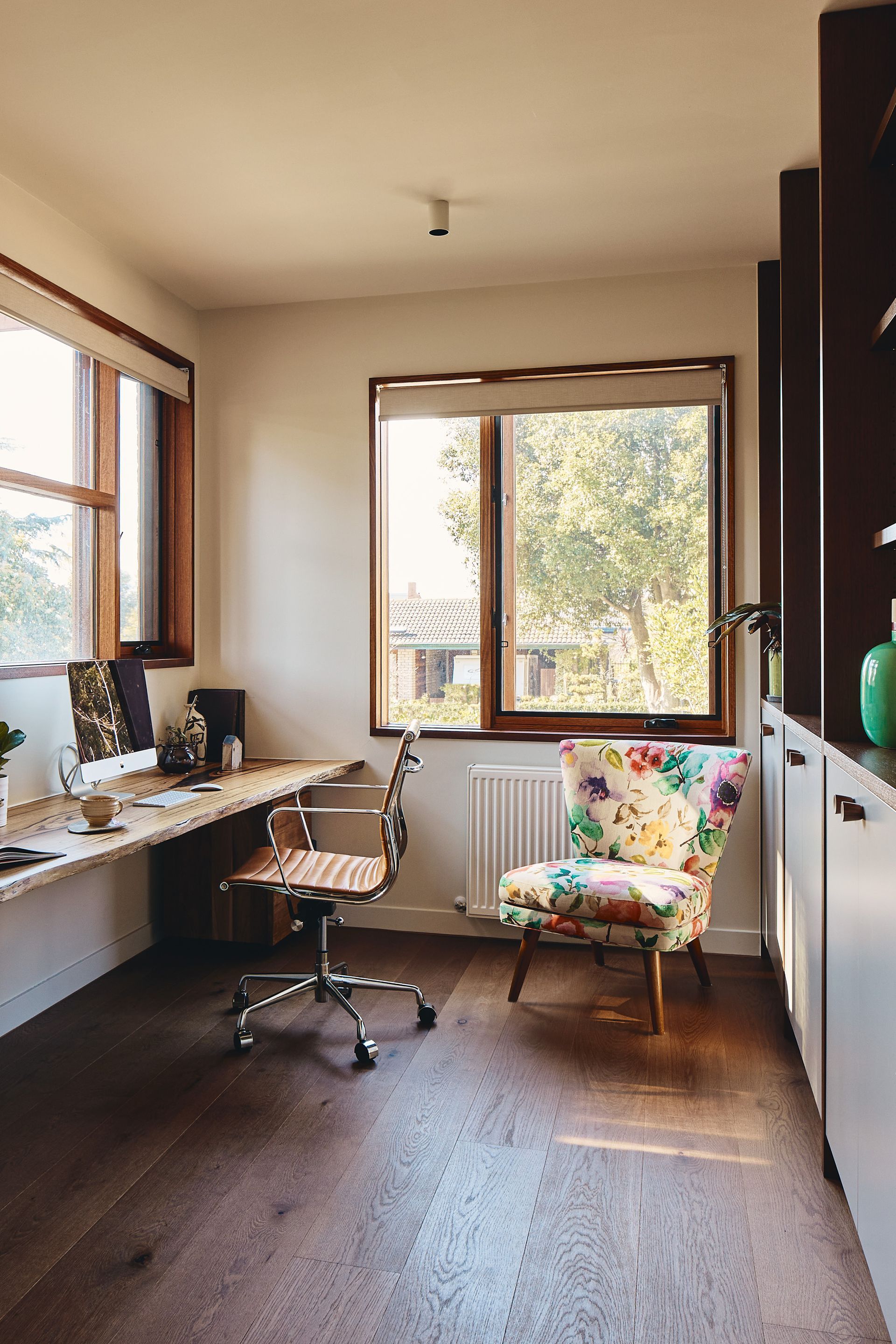 A home office with a desk , chair , and window.