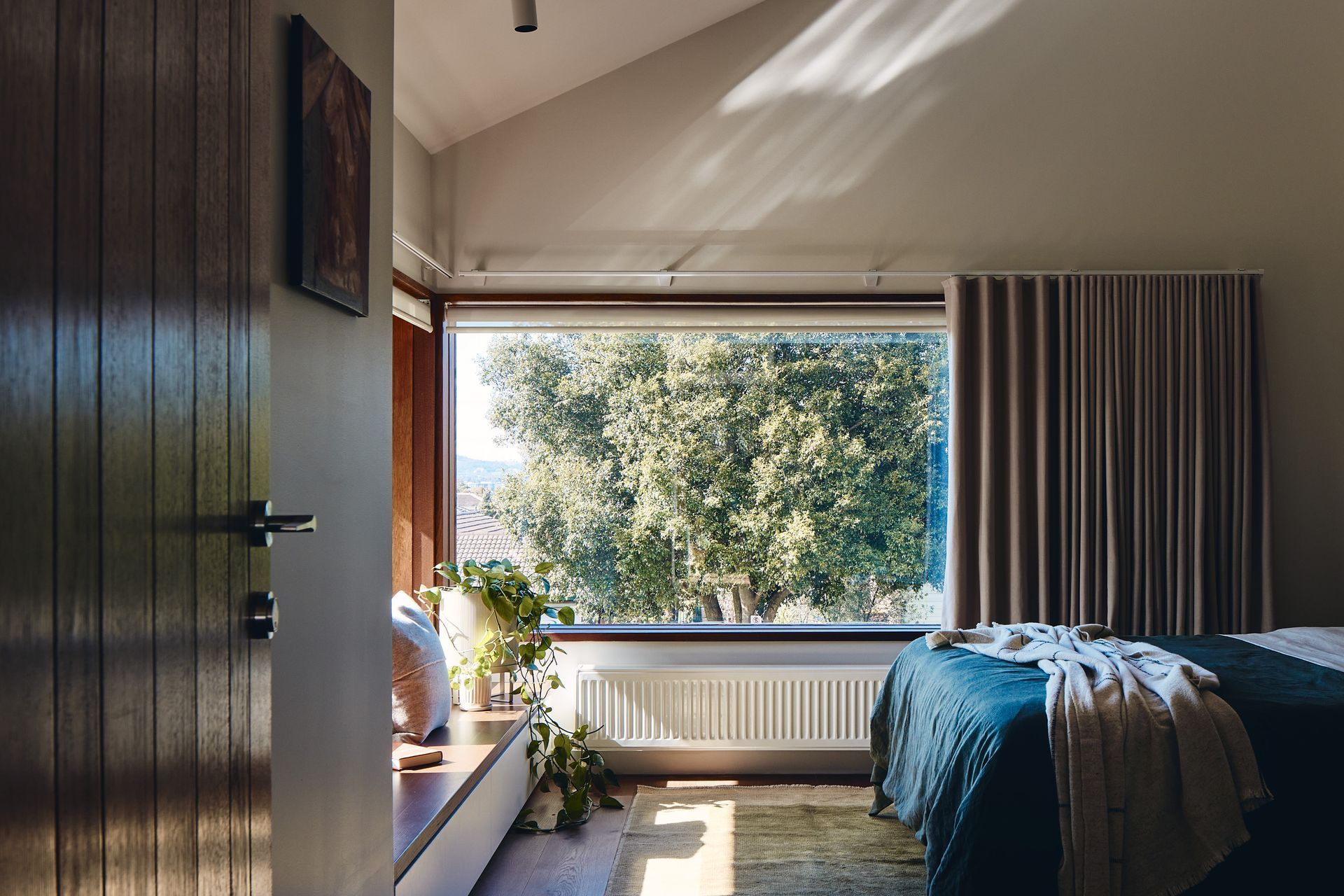 A bedroom with a large window and a bed.