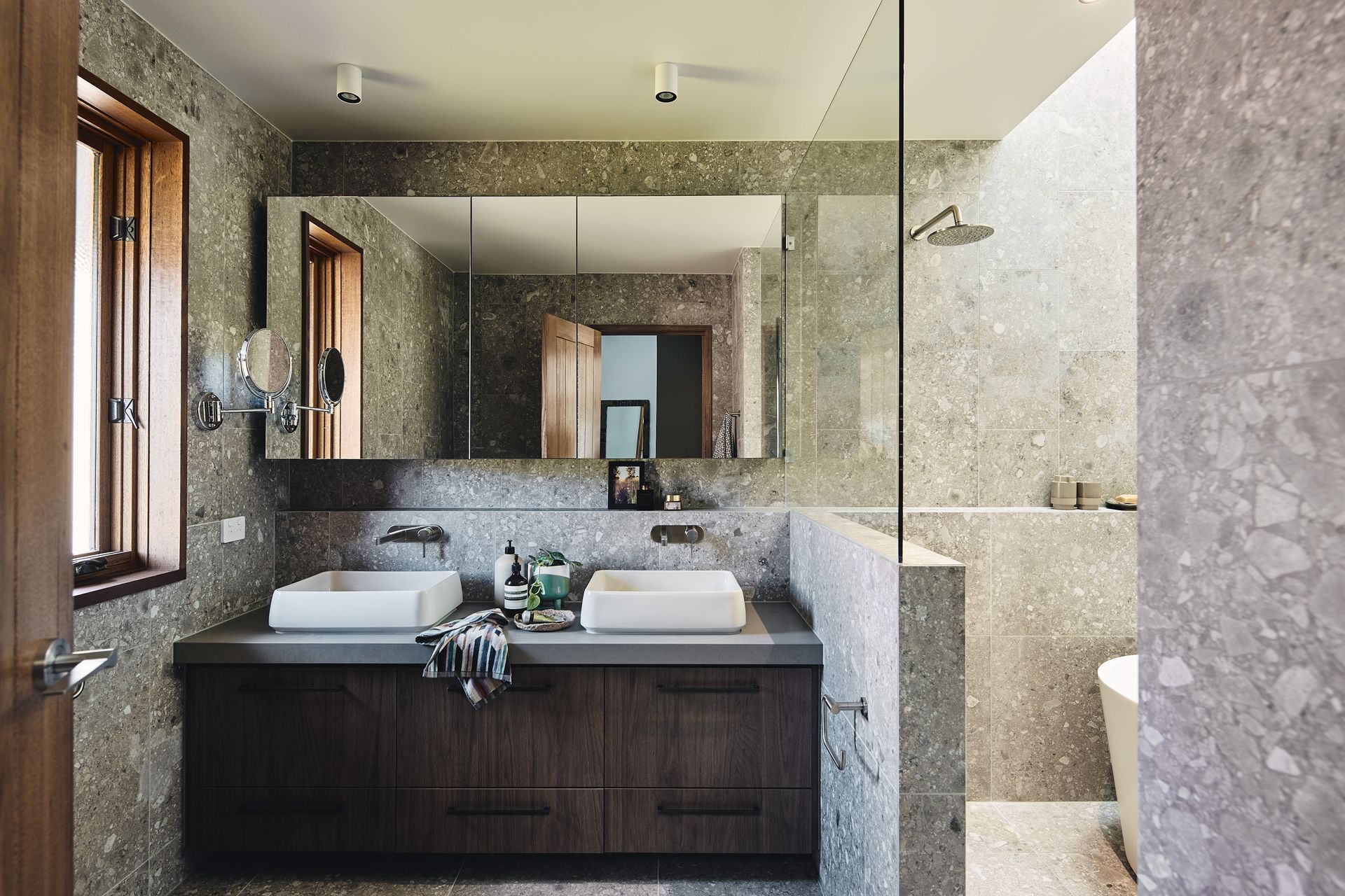 A bathroom with two sinks and a walk in shower.