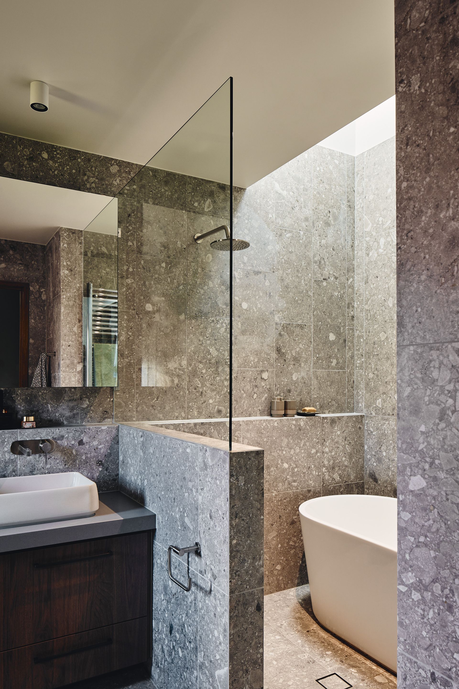 A bathroom with a tub , sink , shower and mirror.