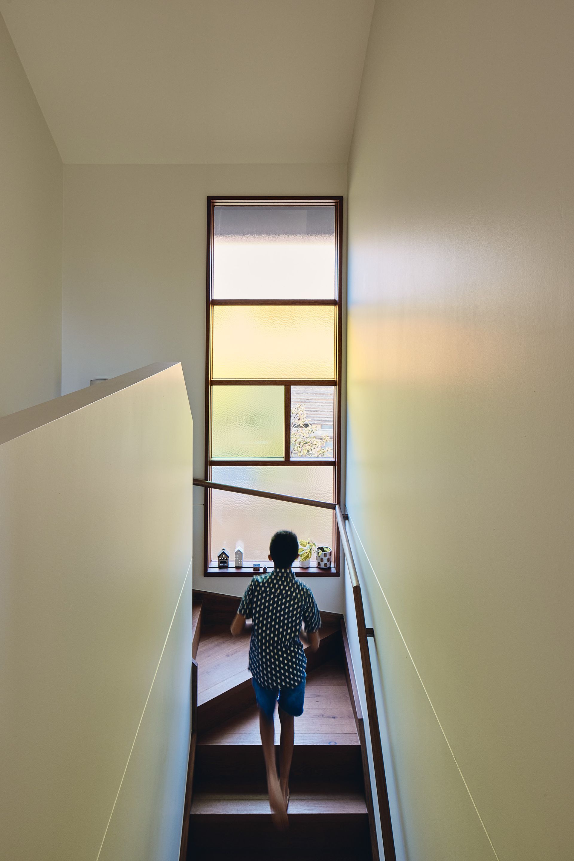 A boy is walking down a set of stairs in a house.