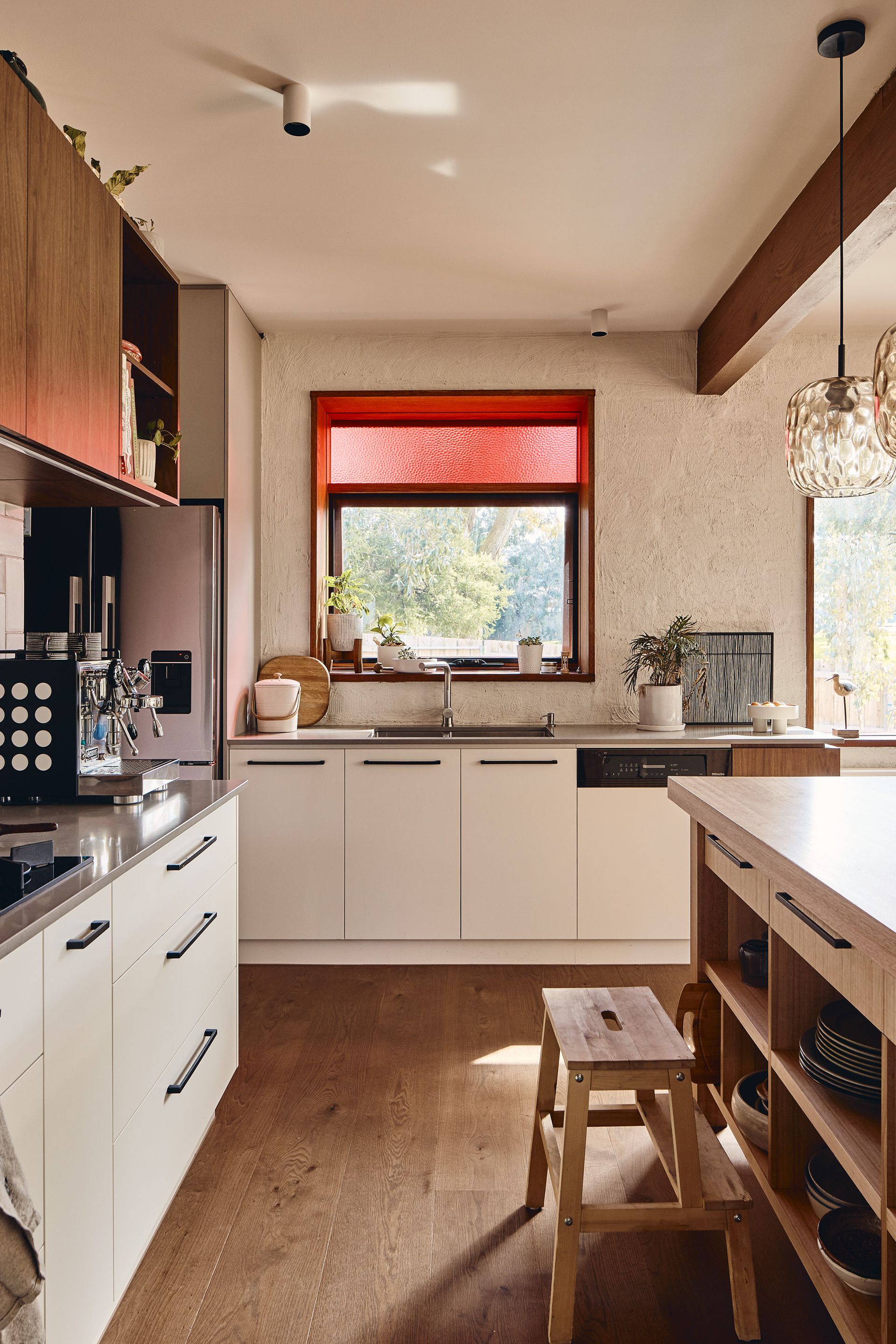 A kitchen with white cabinets , a wooden island , a sink , and a window.