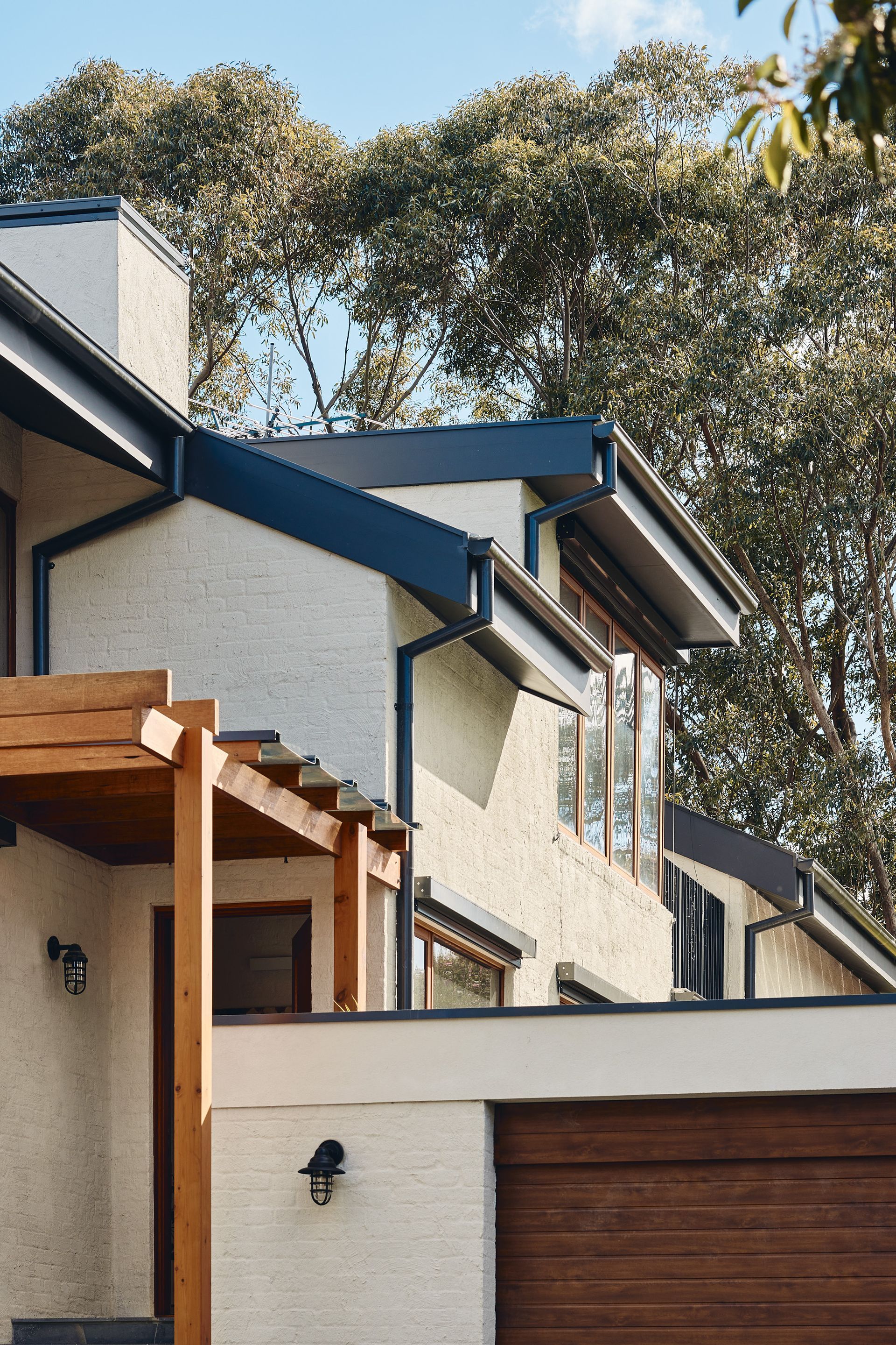 A white house with a wooden garage door and a pergola.