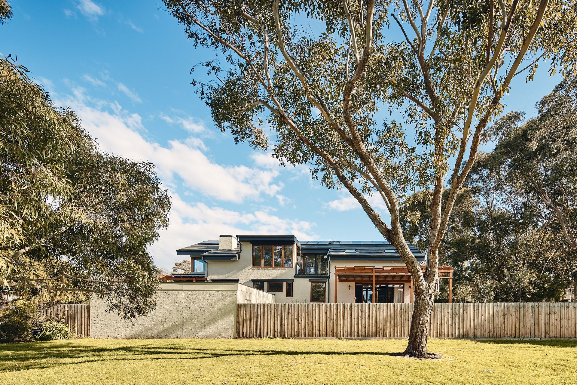 A large house with a wooden fence and a tree in front of it.