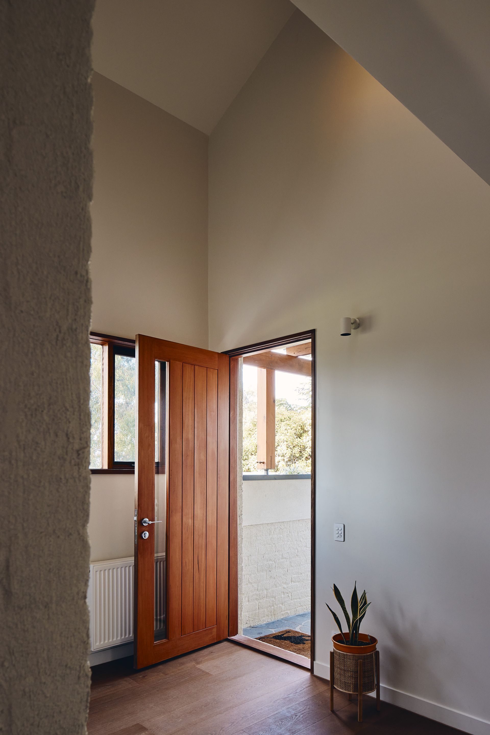 A hallway with a wooden door and a window.