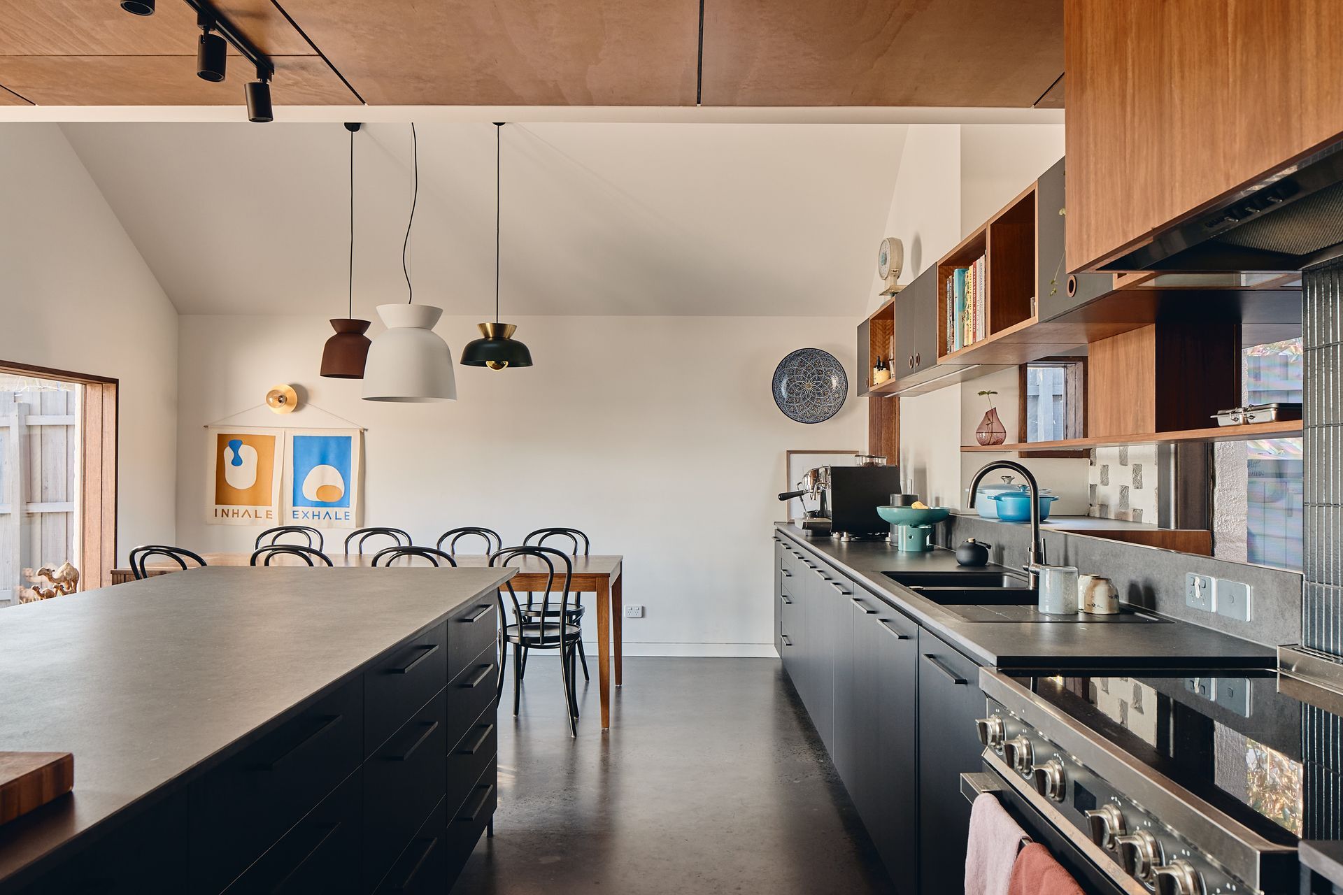 A kitchen with a large island in the middle and a dining room in the background.