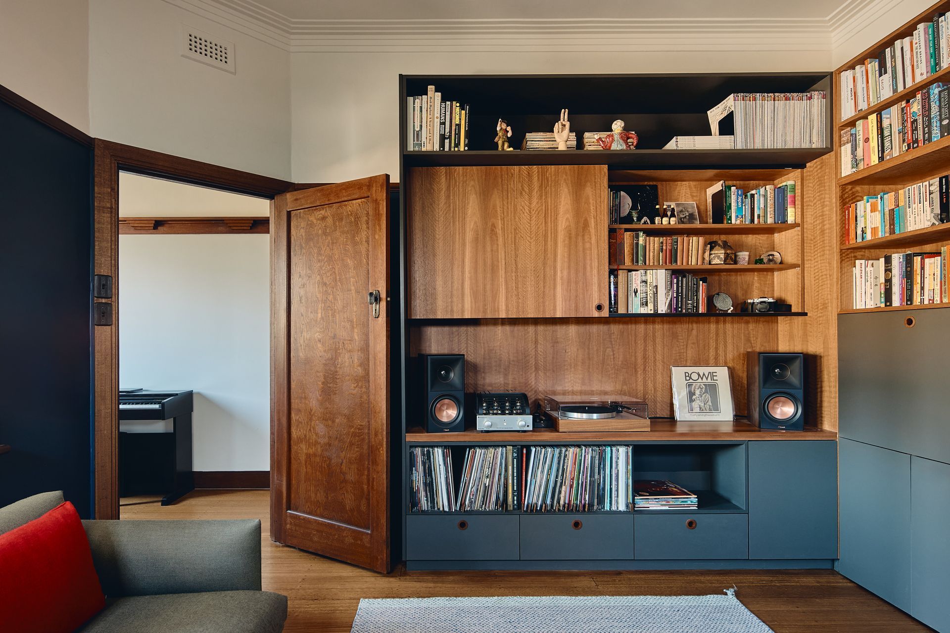 A living room with a couch , bookshelf , and speakers.