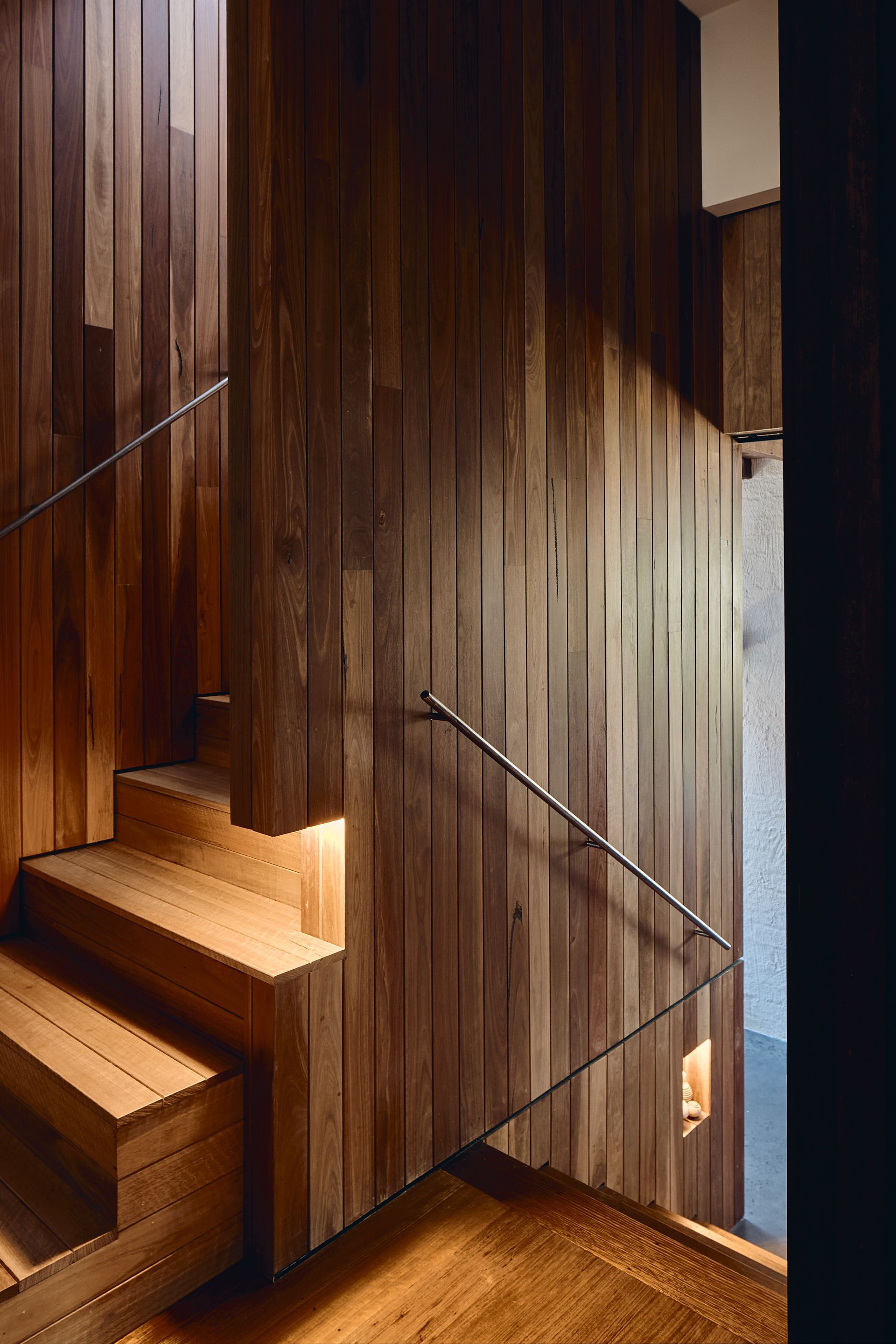 A wooden staircase with a metal railing and a wooden wall