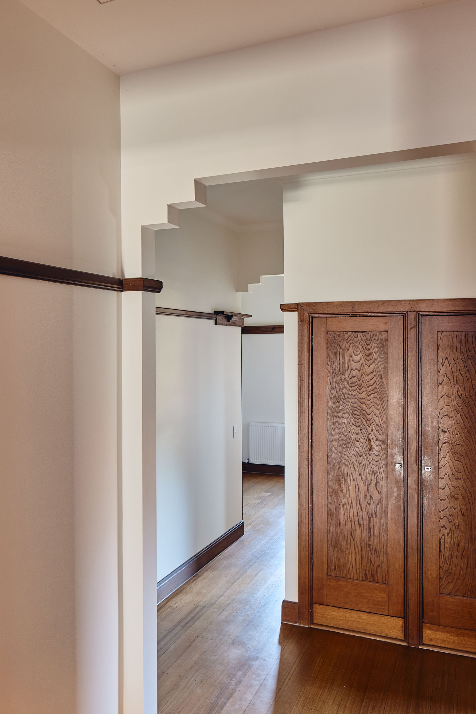 A hallway with wooden doors and white walls