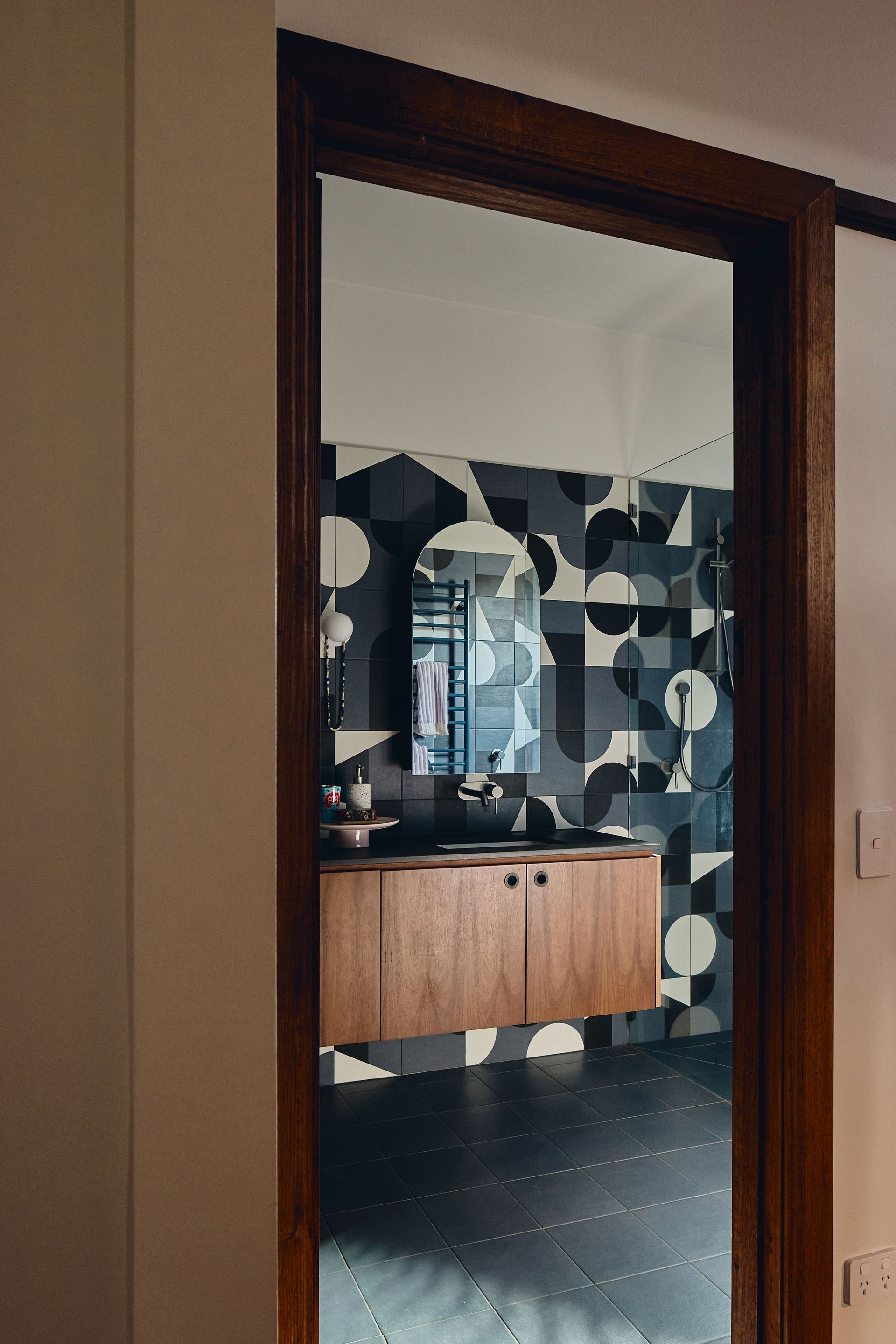 A bathroom with a sink and a mirror is seen through a doorway.