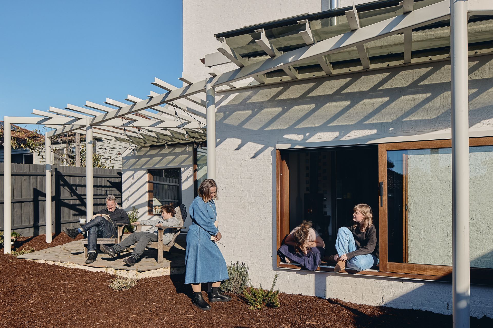 A family is sitting on a window sill in front of a house.