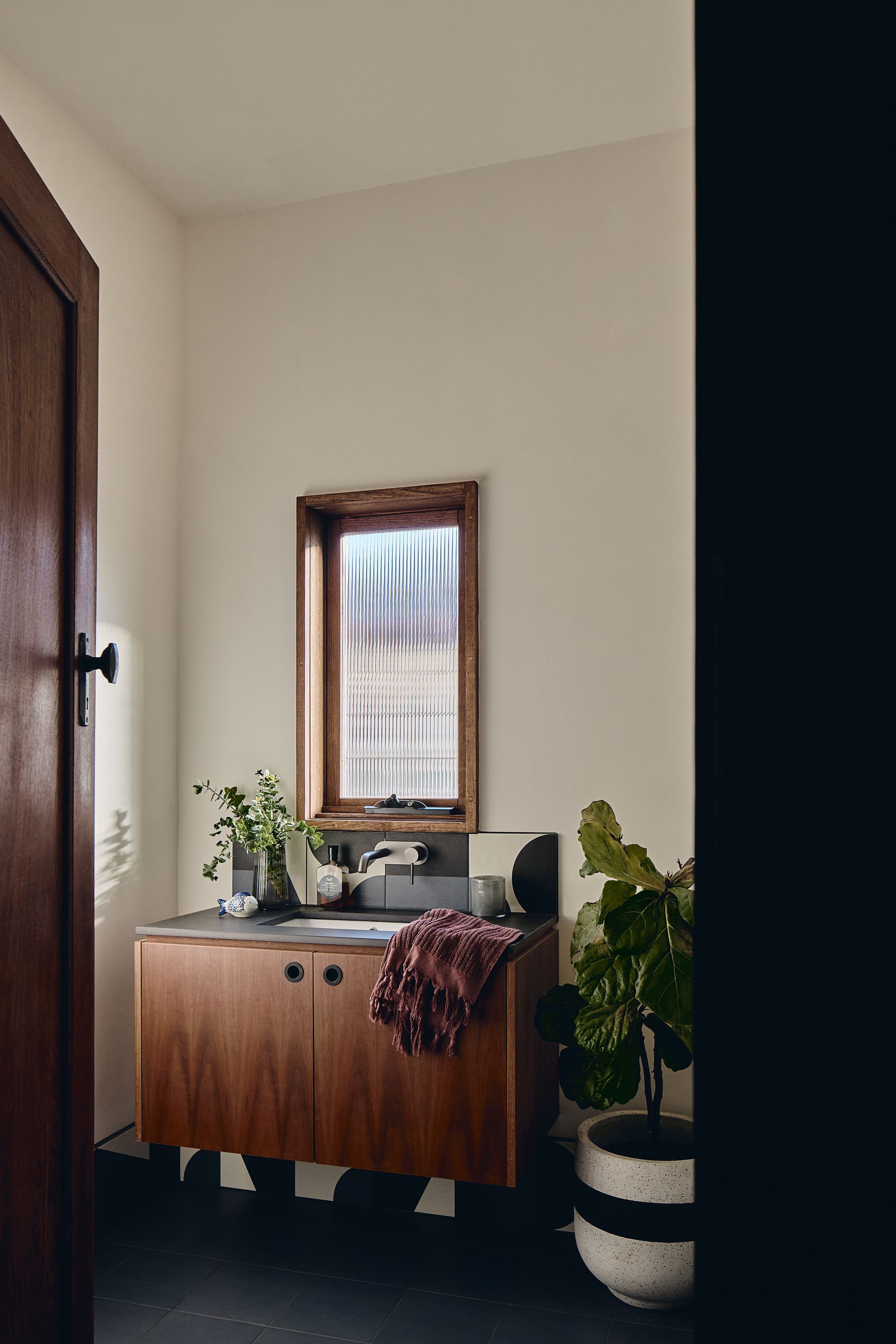 A bathroom with a sink , mirror , and potted plants.