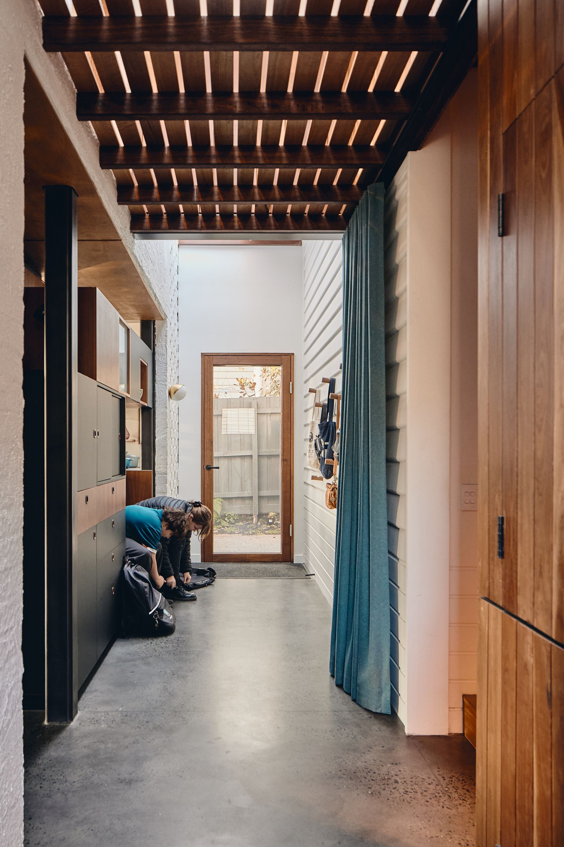 A person is sitting on the floor in a hallway next to a door.