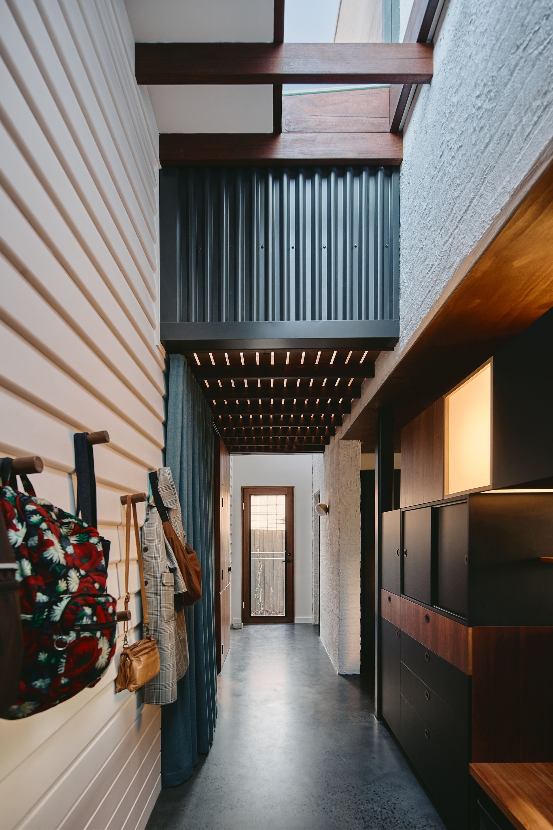 A hallway in a house with bags hanging on the wall.