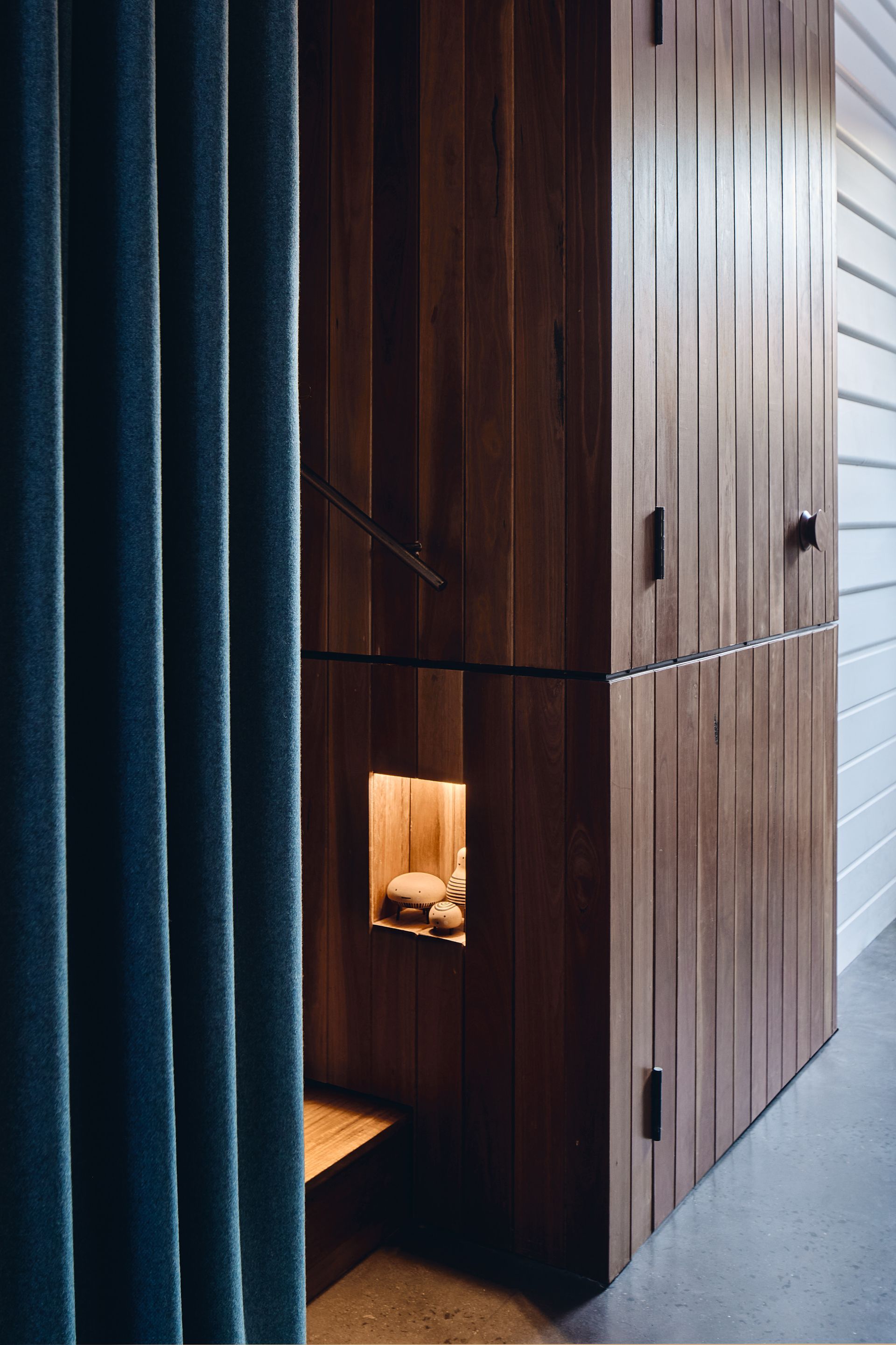 A wooden cabinet with a blue curtain behind it.