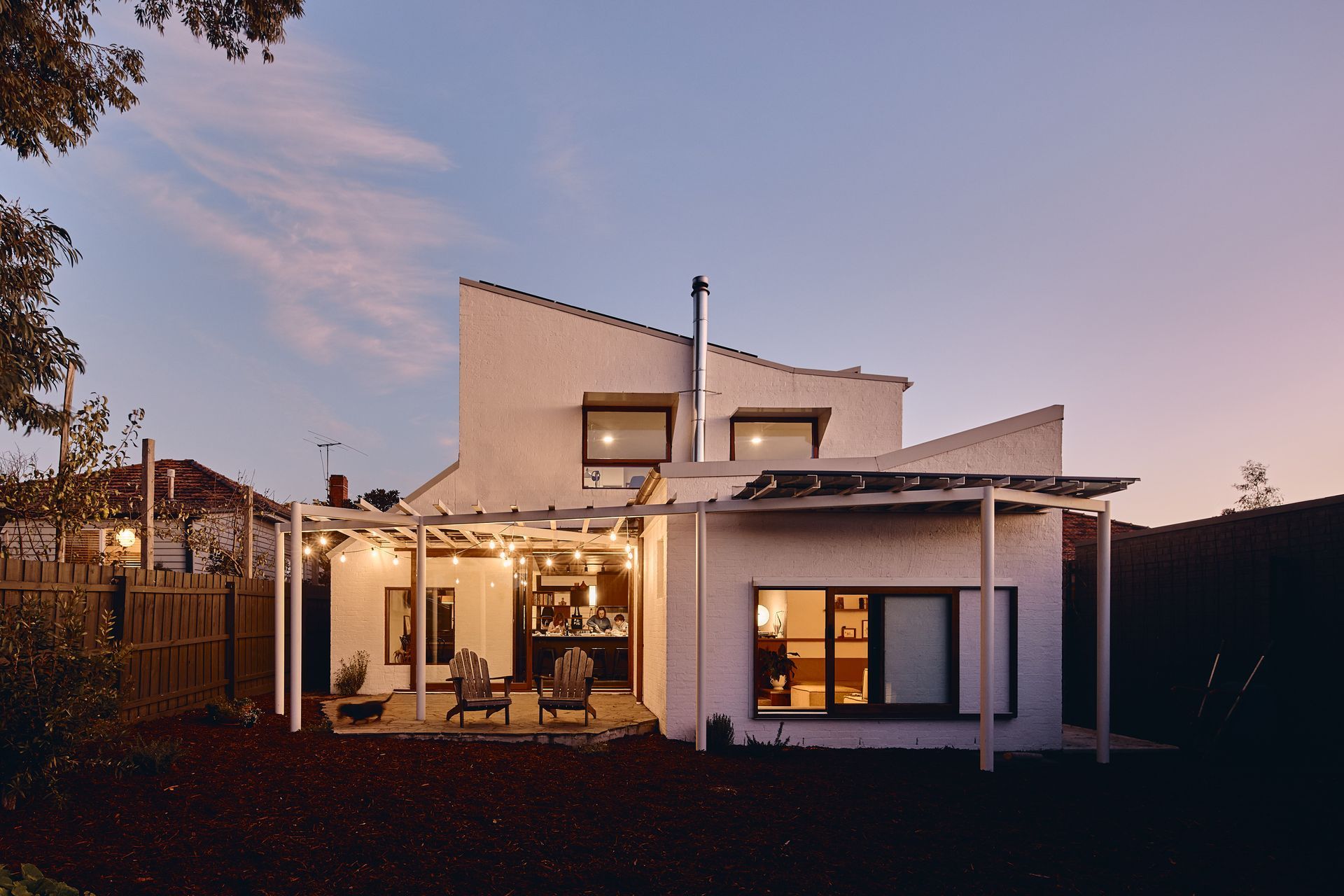 The back of a house with a pergola and lights on it