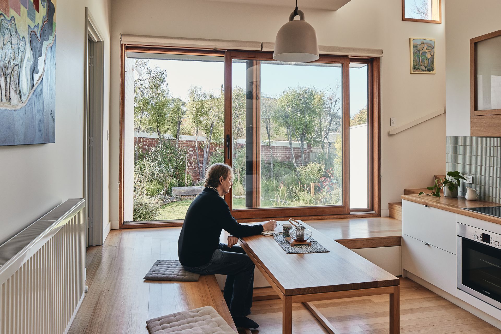 A man is sitting on a bench at a table in a kitchen.