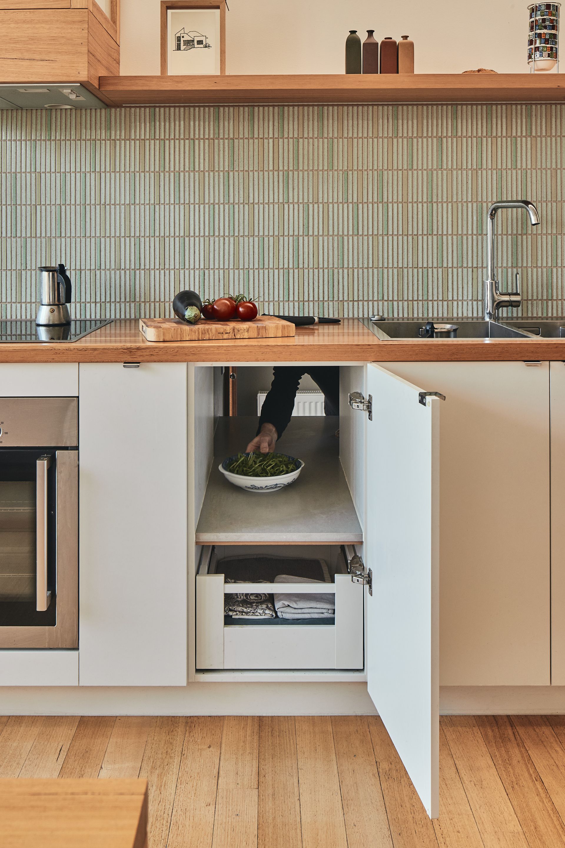 A person is reaching into a drawer in a kitchen