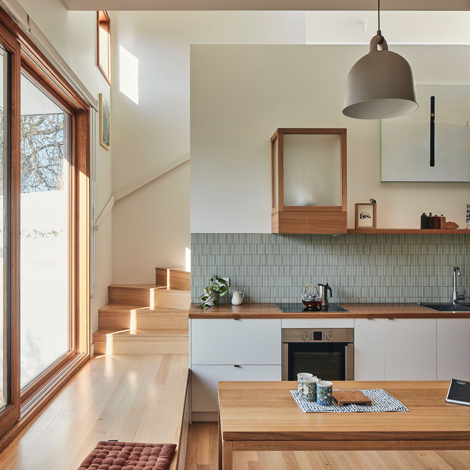 A kitchen with a table and stairs in the background
