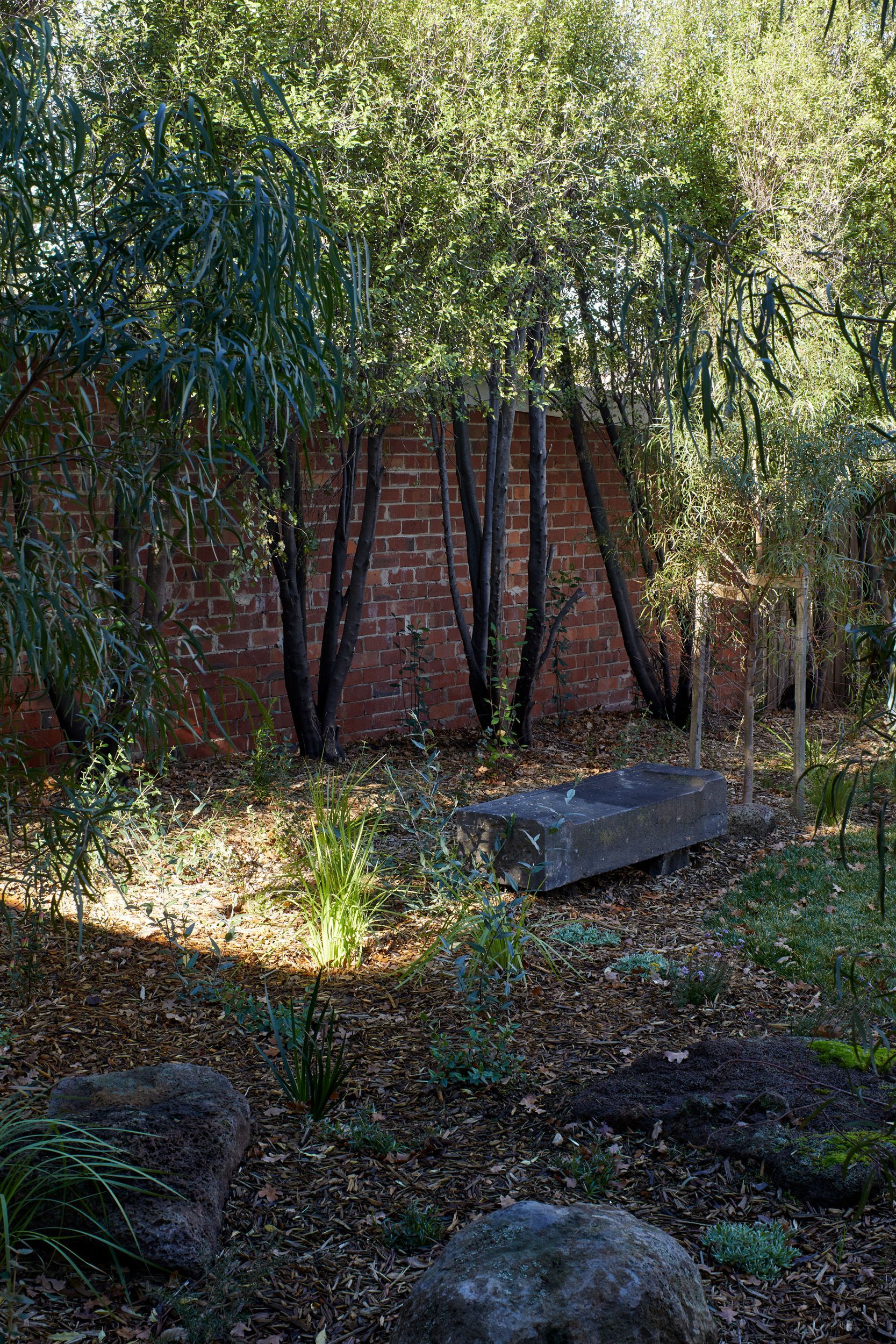 A brick wall is surrounded by trees and rocks in a garden.