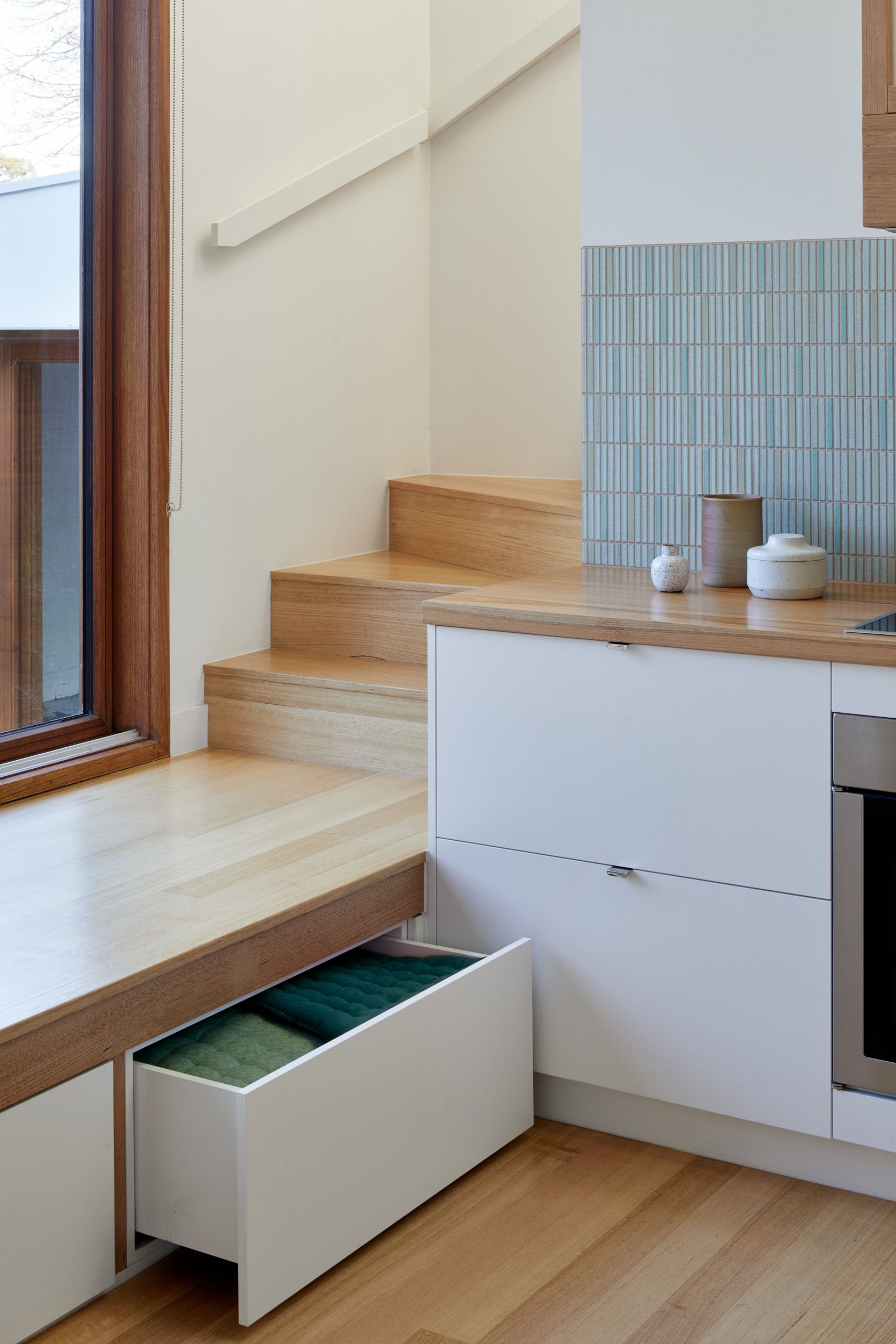 A kitchen with a window seat and drawers underneath it.