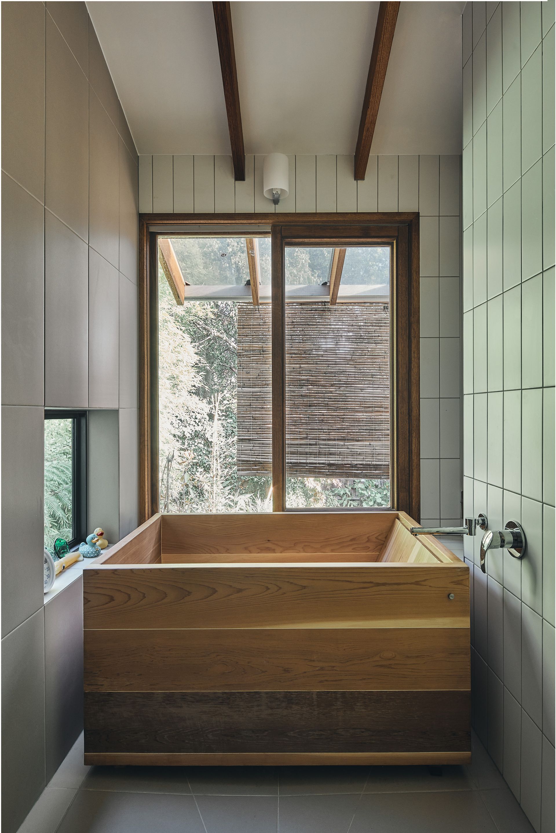 A wooden bathtub in a bathroom next to a window.
