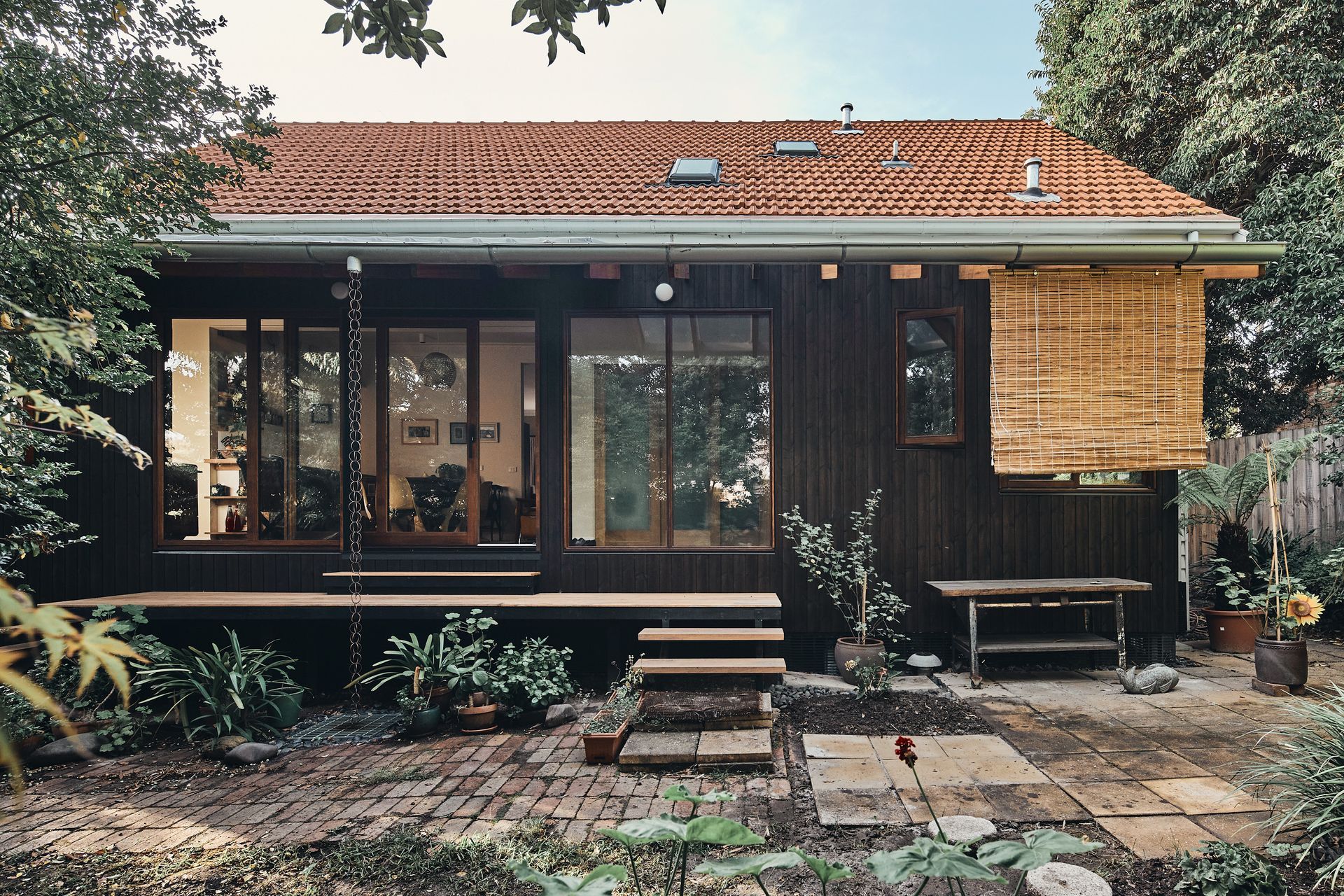 A small house with a red tile roof is surrounded by trees
