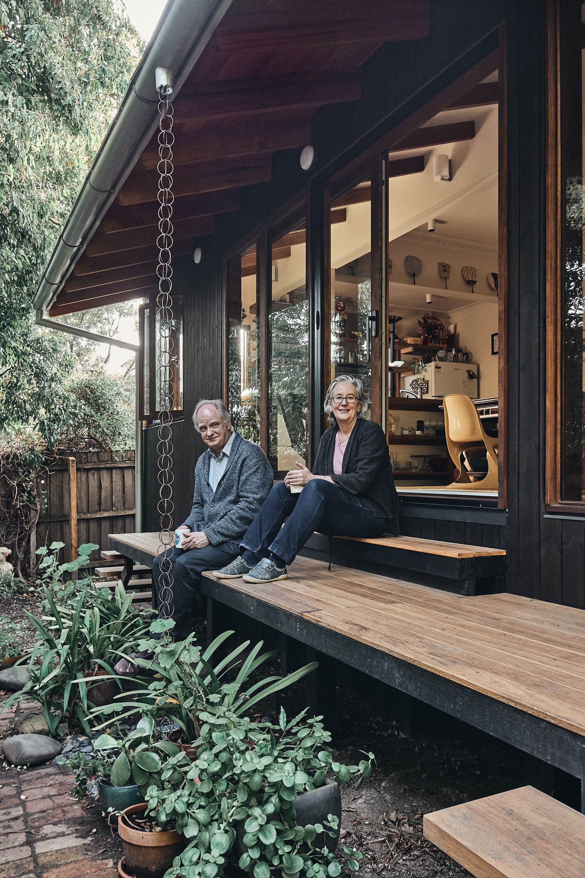 Two men are sitting on the porch of a house.