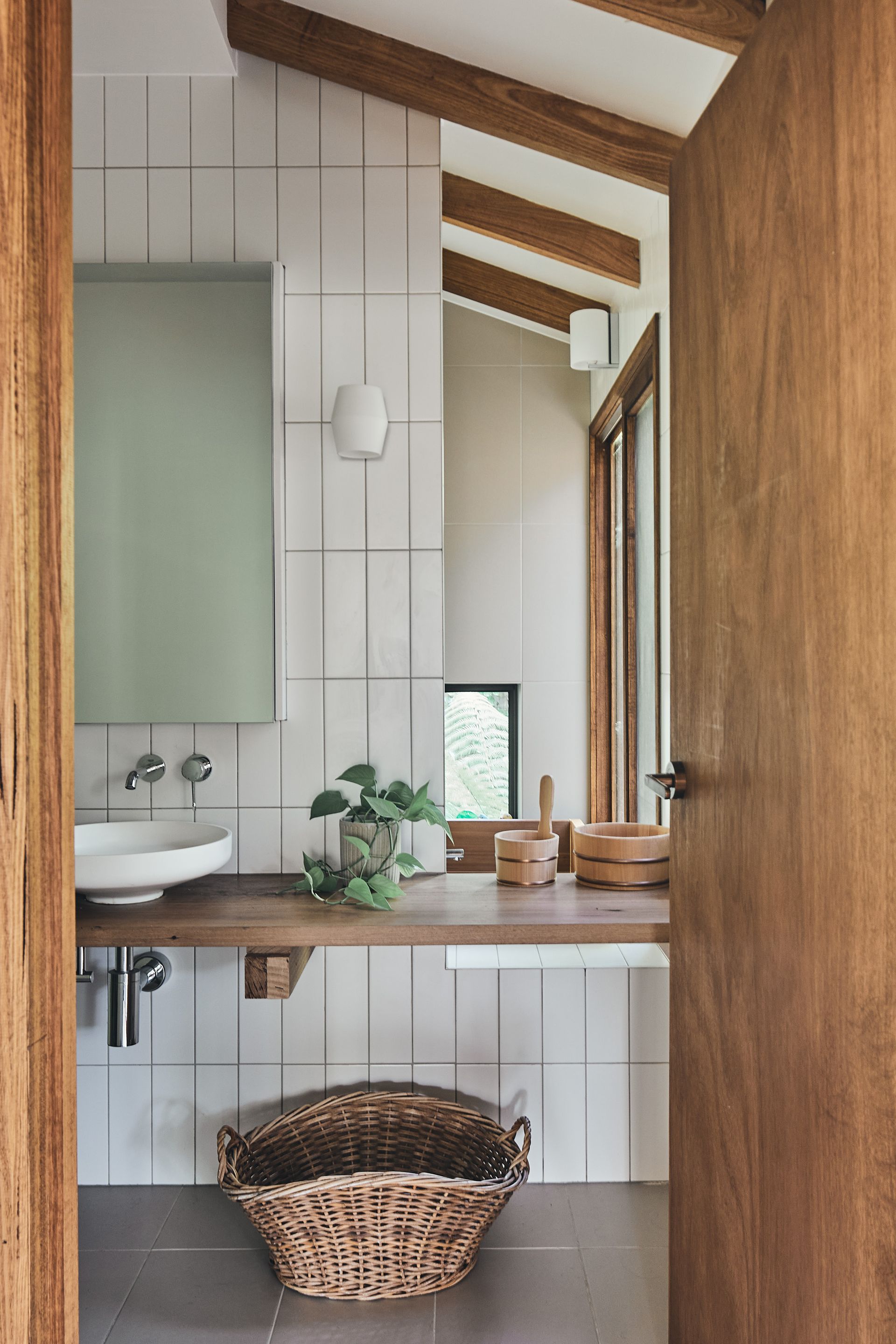 A bathroom with a sink , mirror , and wicker basket.
