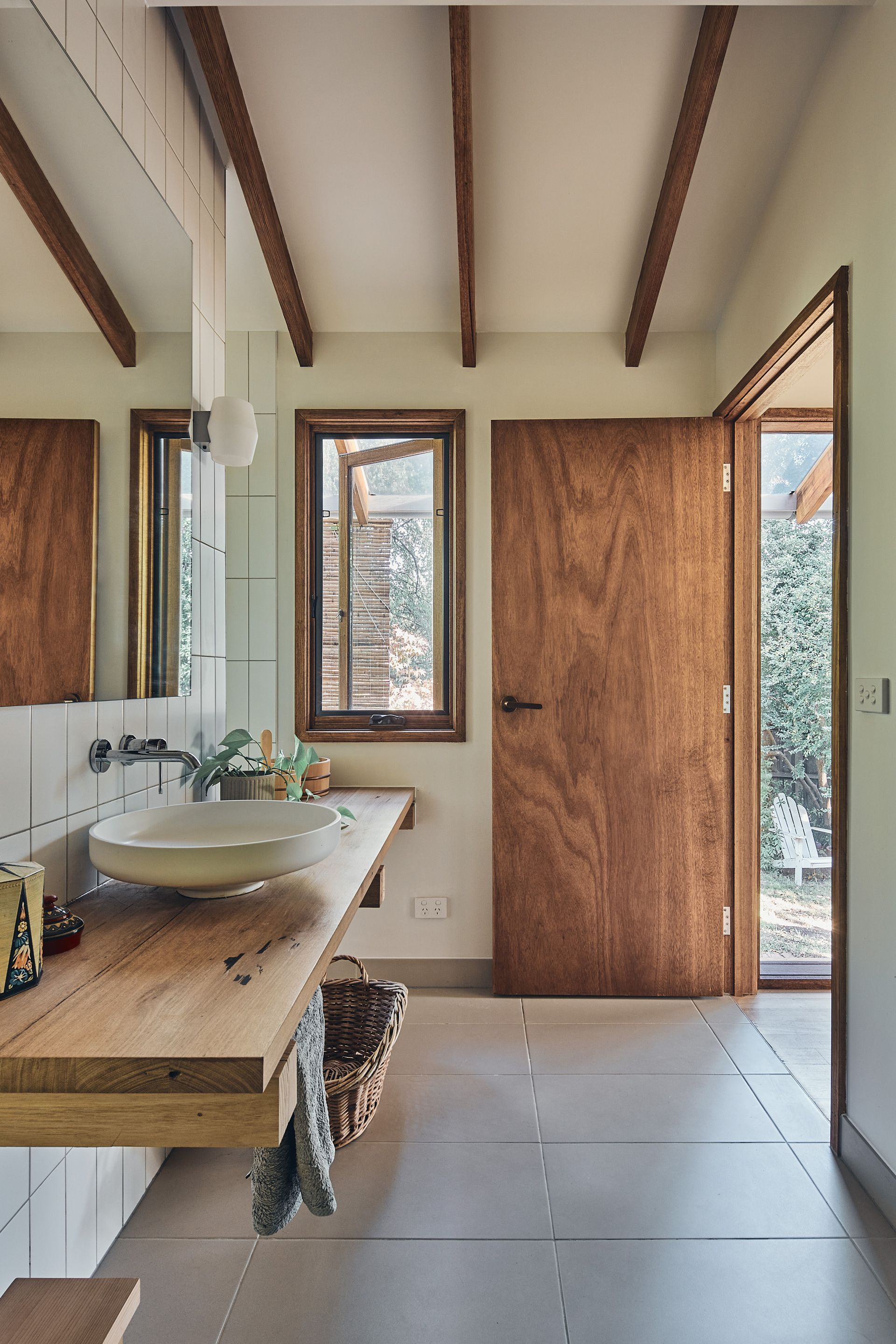 A bathroom with a sink , mirror , and wooden door.
