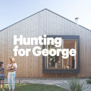 A woman and a child are standing in front of a wooden house.