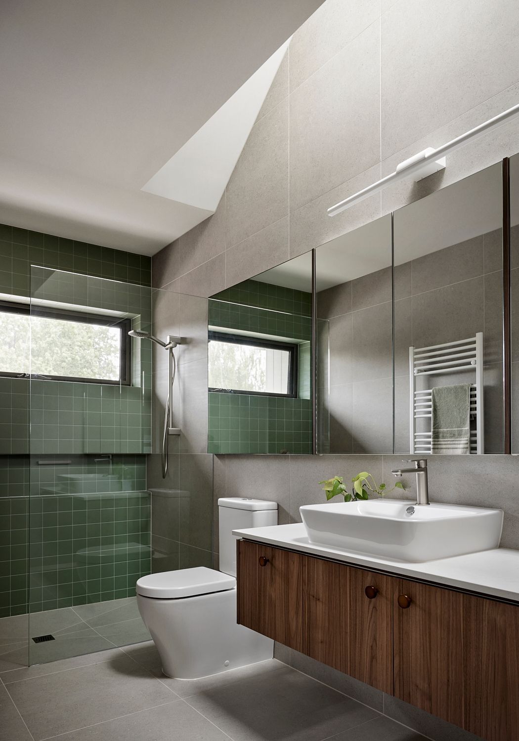 A bathroom with a toilet , sink , mirror and shower.