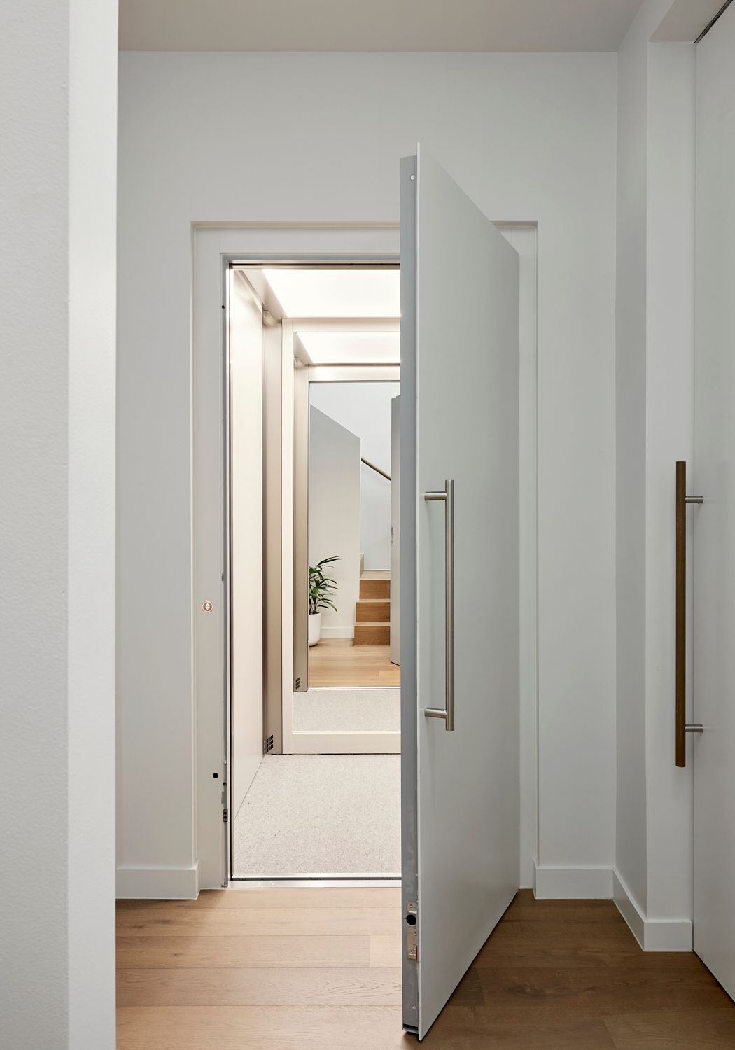 A white door is open in a hallway leading to a staircase.