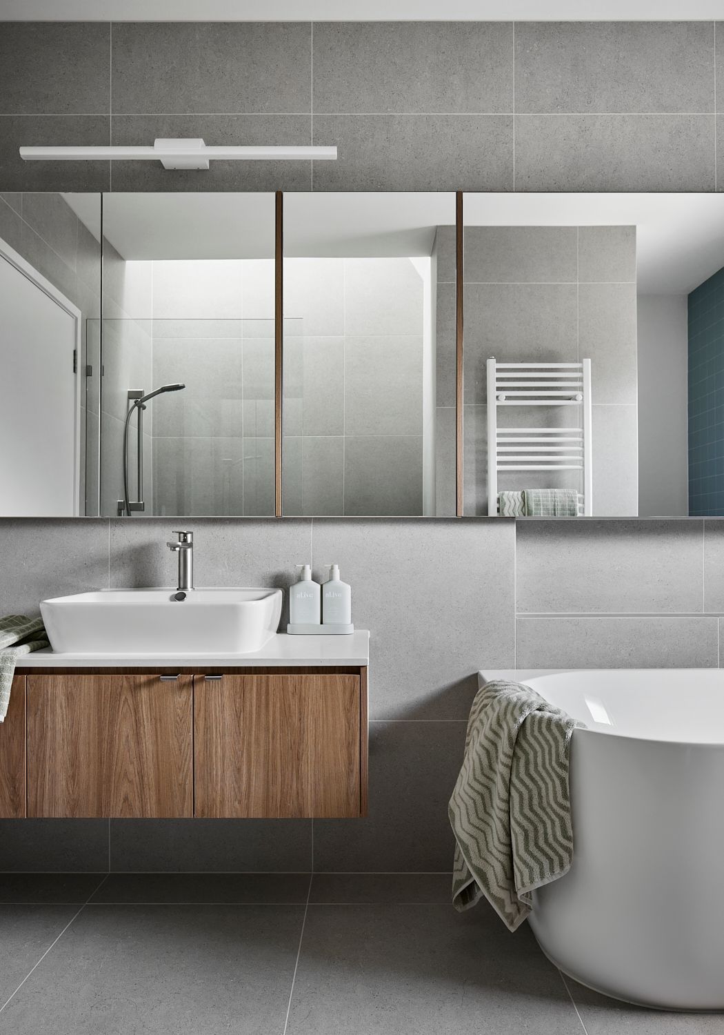 A bathroom with a sink , bathtub , mirror and towel rack.