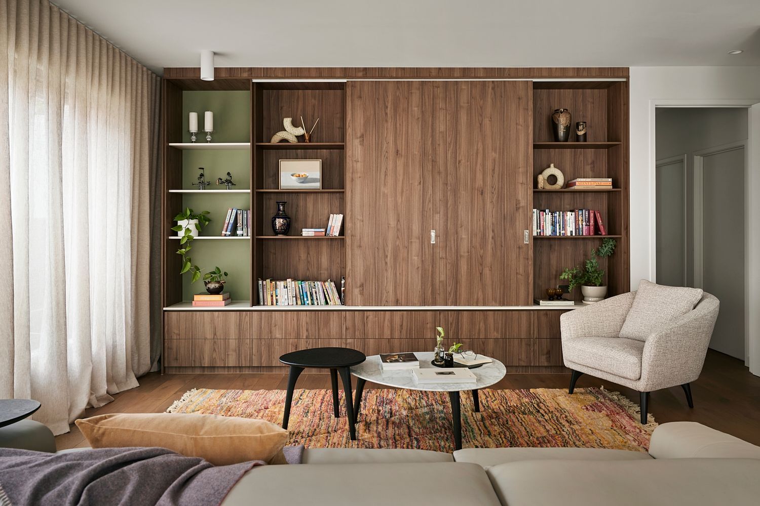 A living room with a couch , chair , coffee table and shelves.