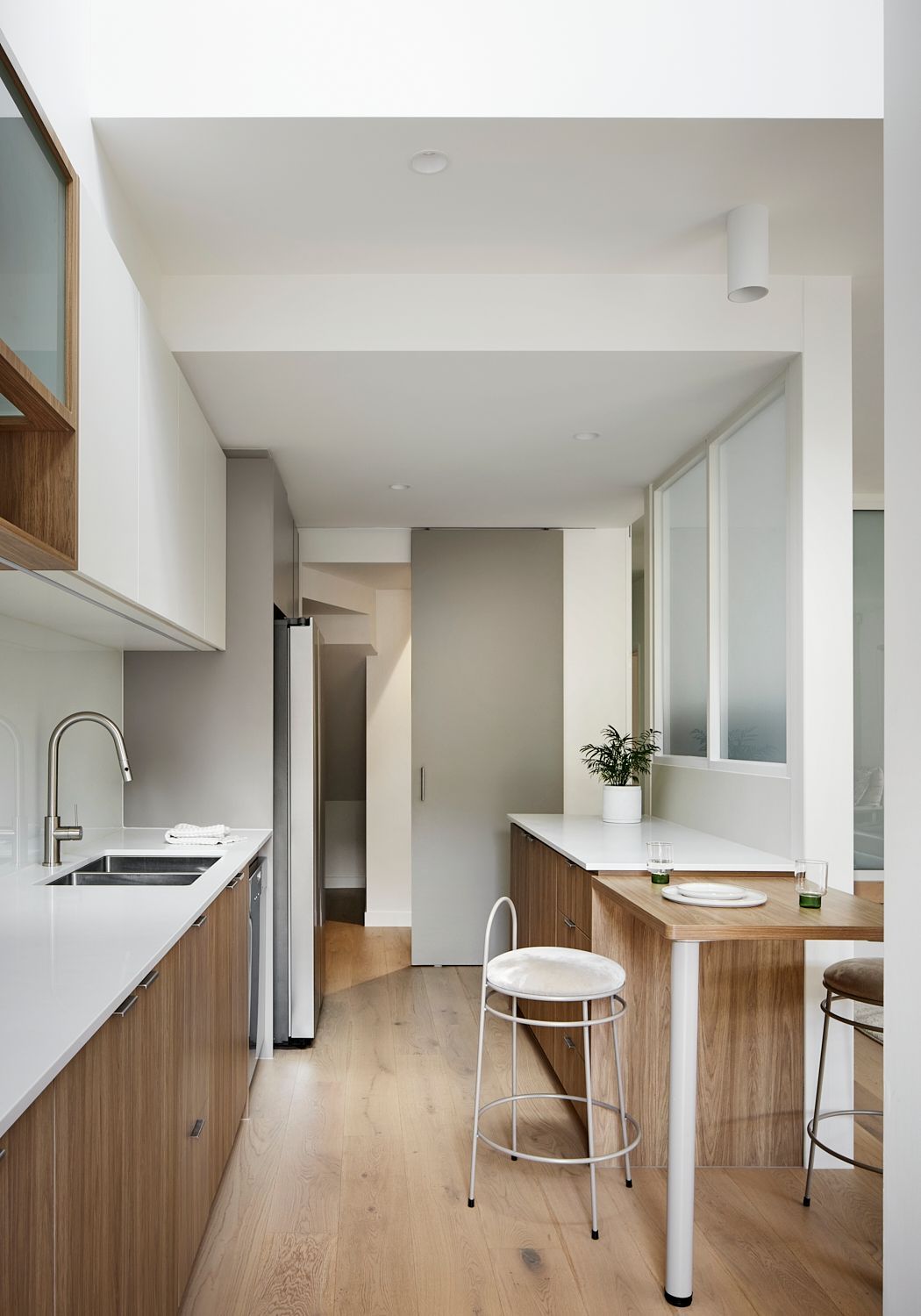 A kitchen with wooden cabinets , a sink , a table and a chair.