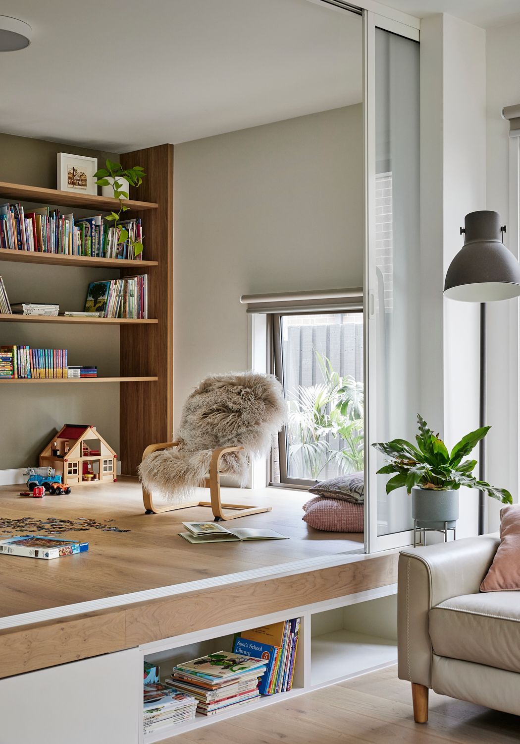 A living room with a couch , chair , shelves and a window.