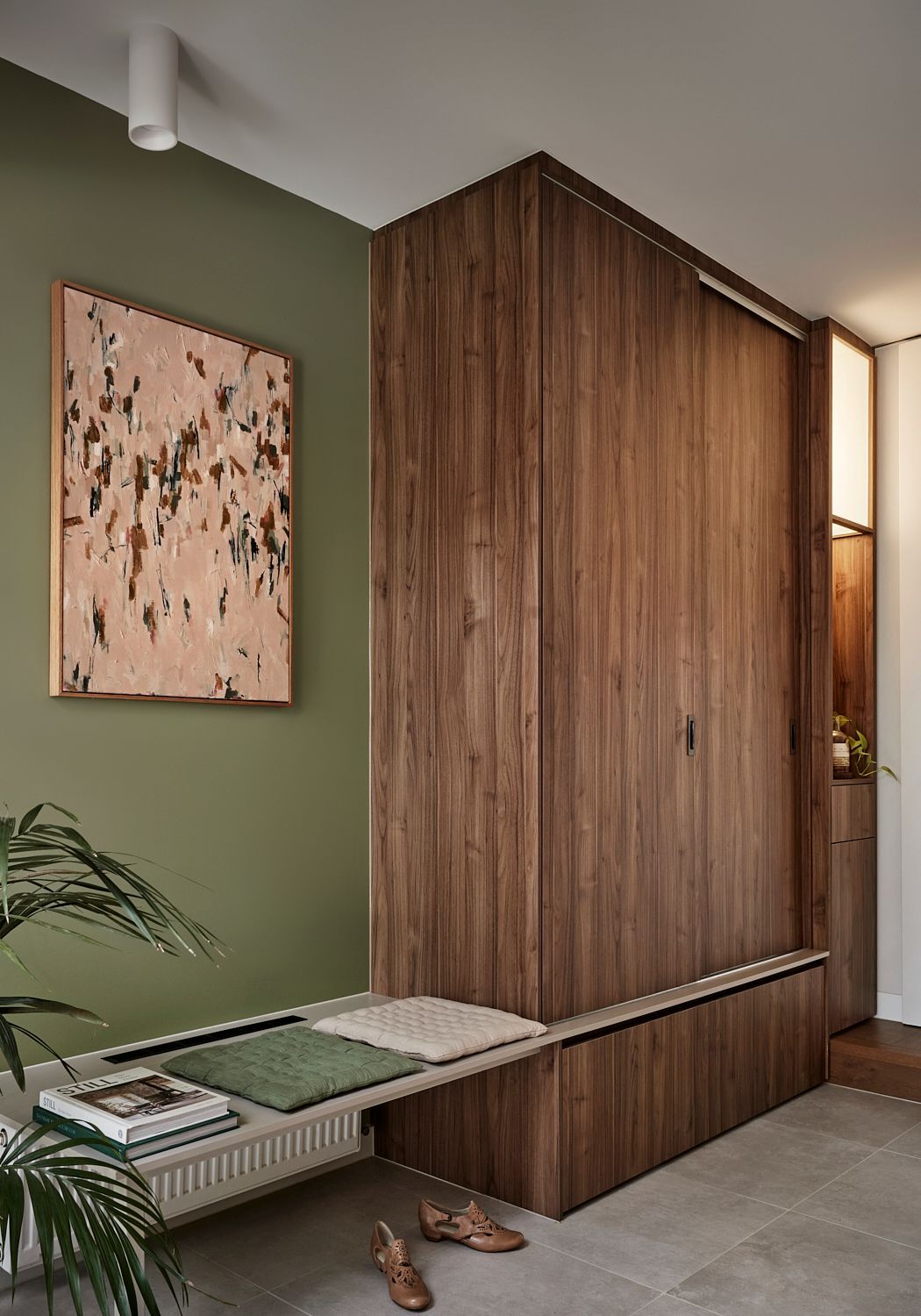 A hallway with a wooden bench and a painting on the wall.