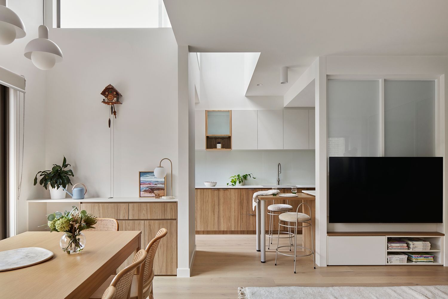 A living room with a dining table and chairs and a television.